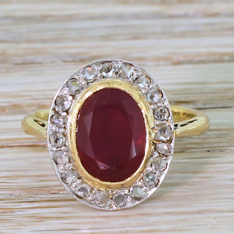 A mavellous vintage ruby ring. The oval cut centre stone displays a rich, deep pigeon blood red and is rubover set in milgrained yellow gold. Twenty white and bright rose cut diamond are set in the platinum surround, above a striking vented gallery.