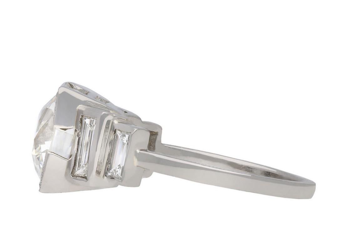 Art Deco diamond flanked solitaire ring. Centrally set with a cushion shape old mine diamond, I colour, VVS2 clarity, with a weight of 3.50 carats, in an open back square claw setting, flanked by two rectangular baguette cut diamonds in open back