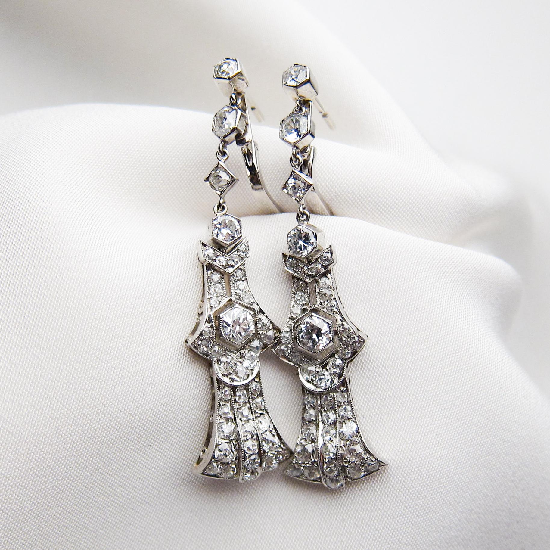 Circa 1920. Each of these fantastic Deco dangle earrings features a central round brilliant-cut diamond (two total) weighing .54 carats combined with an SI1-SI2 clarity and G-H color. 41 round old European-cut diamonds (82 total) accent each