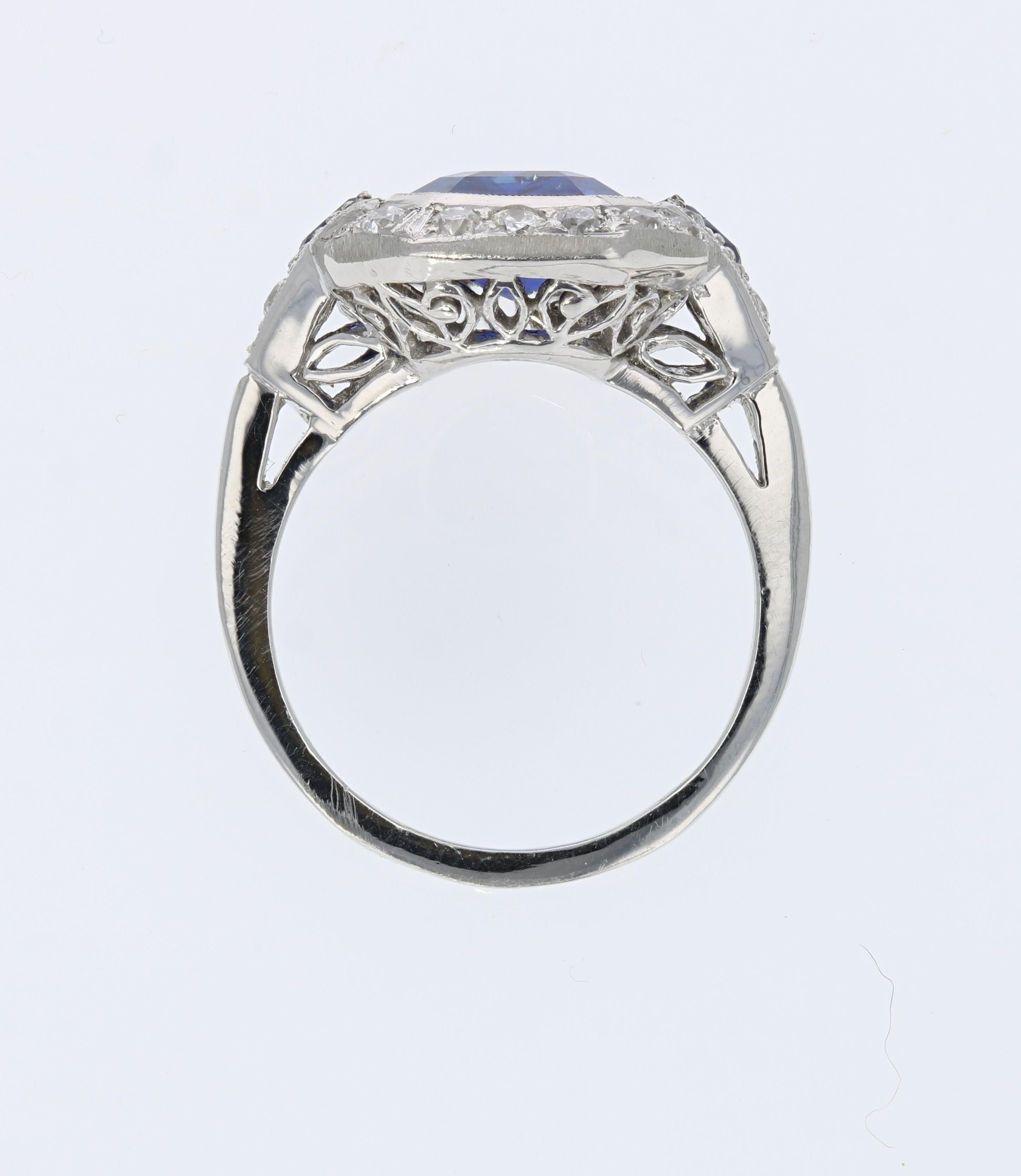 This Art Deco style platinum estate ring is centered by an emerald-cut blue sapphire that weighs approximately 3.55 carats. The sapphire is accented by 2 pear-shaped blue sapphires weighing approximately 0.10 total carats, and 20 old mine-cut