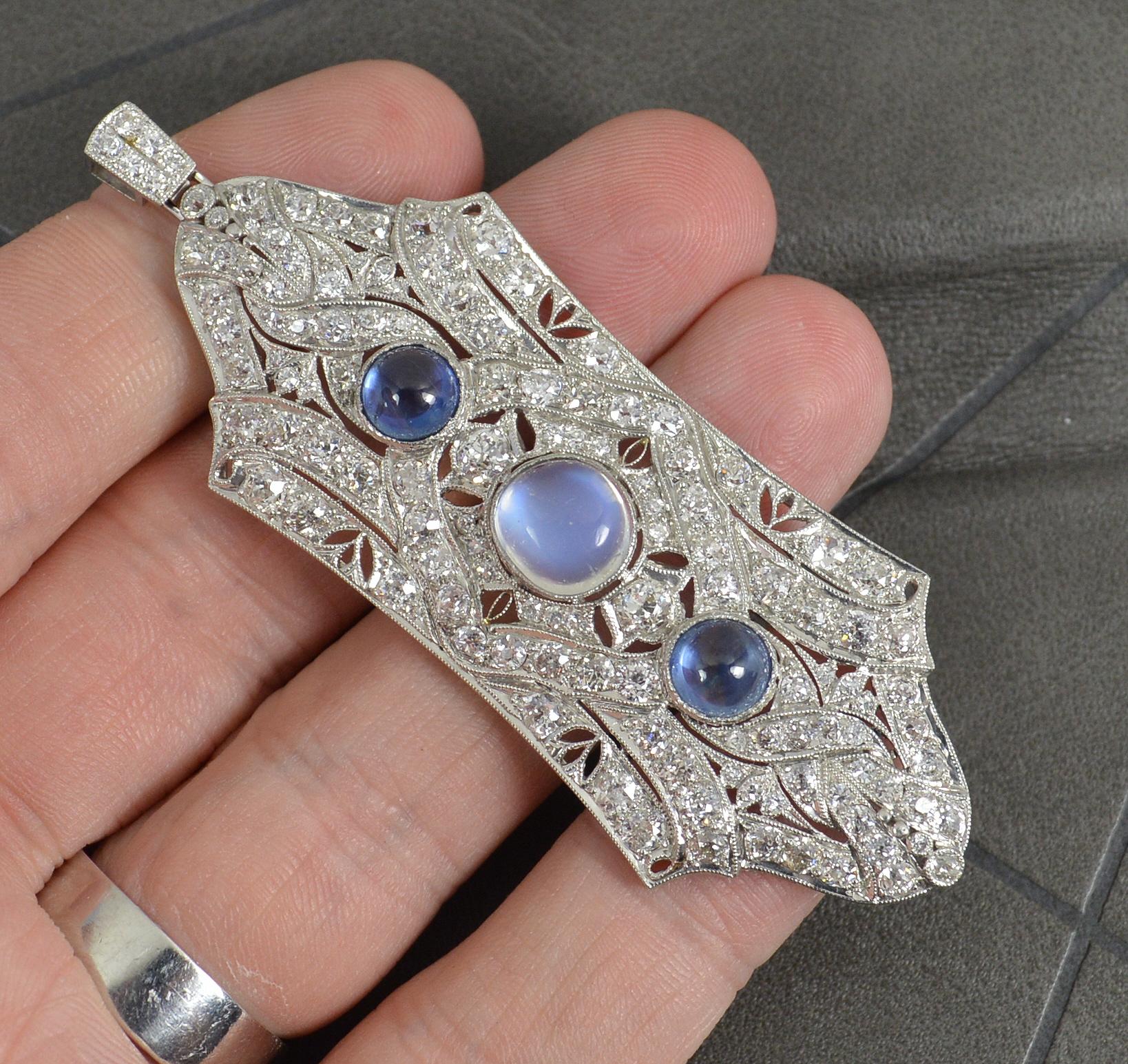 A fantastic Art Deco period pendant. Circa 1920/30.
Solid platinum example.
Designed with a large blue moonstone to centre with a sapphire cabochon above and below with many old cut diamonds set throughout the piece.
Minimum of 3.75 carats of