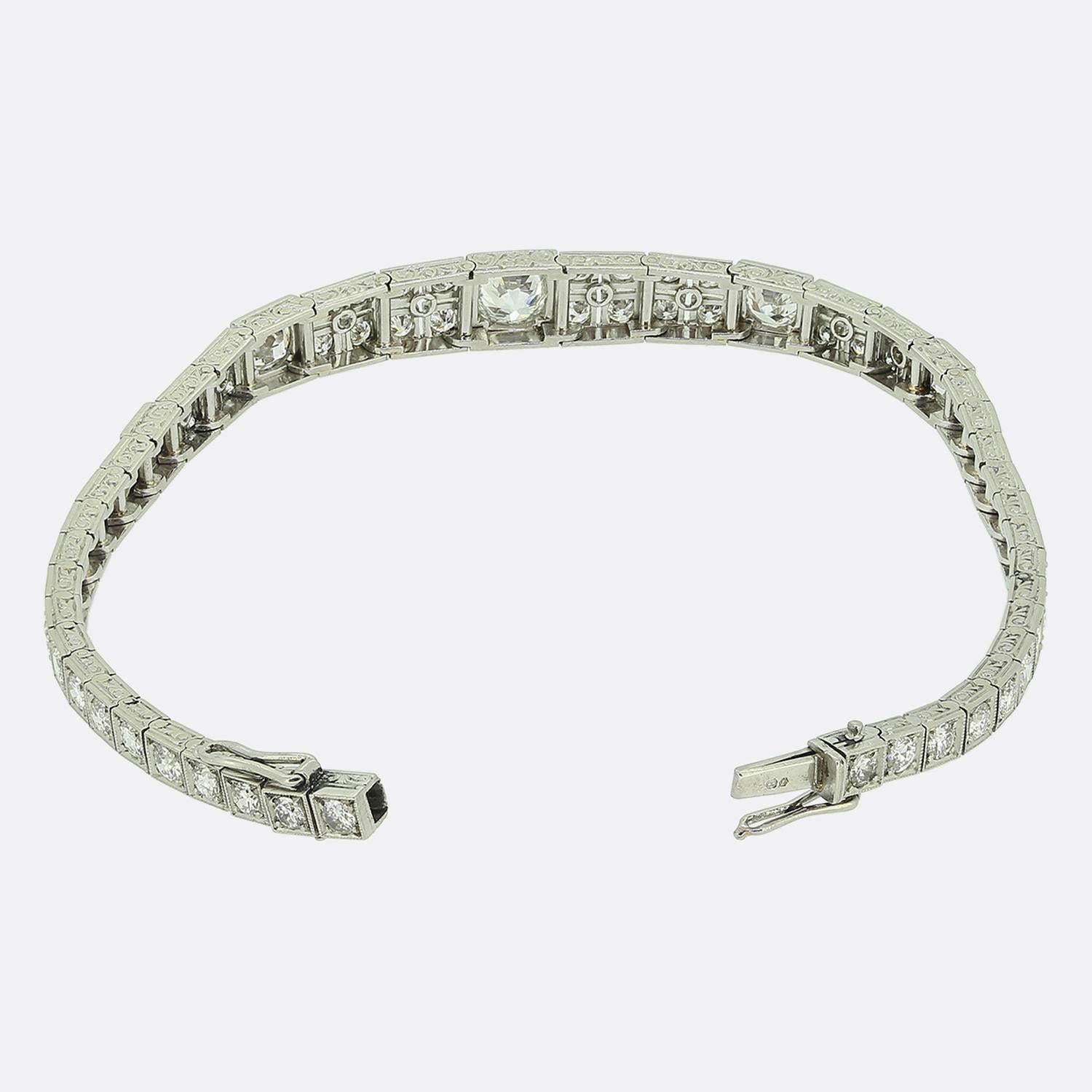 Aquí tenemos una encantadora pulsera de los años 30, que encarna el estilo Art Déco. Esta pieza está meticulosamente elaborada con una serie de eslabones cuadrados, cada uno engastado con diamantes redondos facetados de talla antigua. La sección