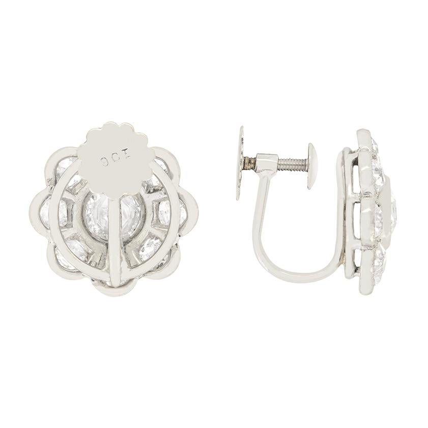 These endearing pair of diamond cluster earrings date back to the artistic Art Deco era. Set to centre of each earring is a 0.70 carat old cut with smaller eight cut diamonds surrounding in the daisy halo. The eight cut diamonds total to 0.15 carat