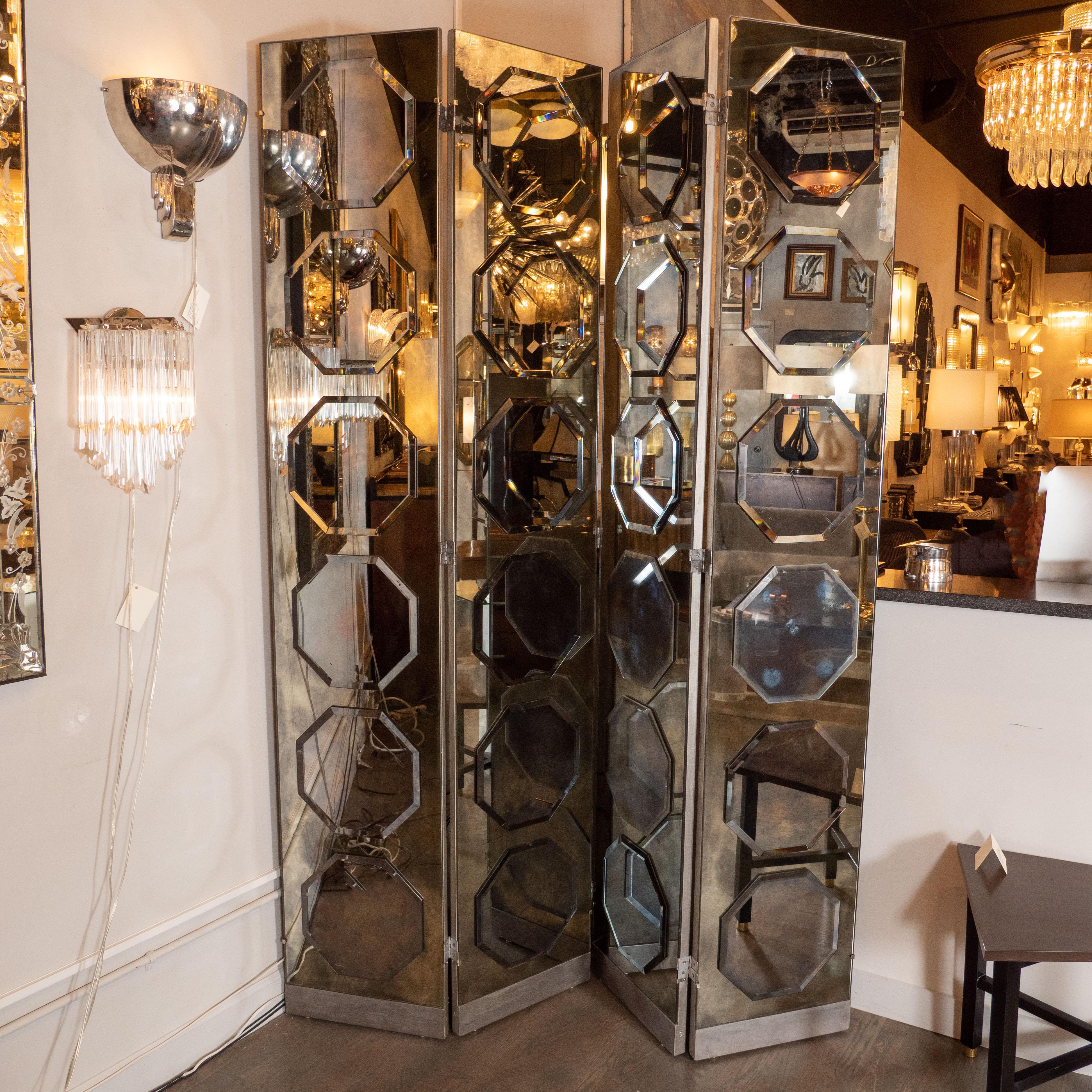 This glamorous and elegant four-panel Art Deco Hollywood screen was realized in France, circa 1940. It offers four rectangular panels in smoked antique mirror- each replete with six octagonal appliqués on each panel. The back of each panel is