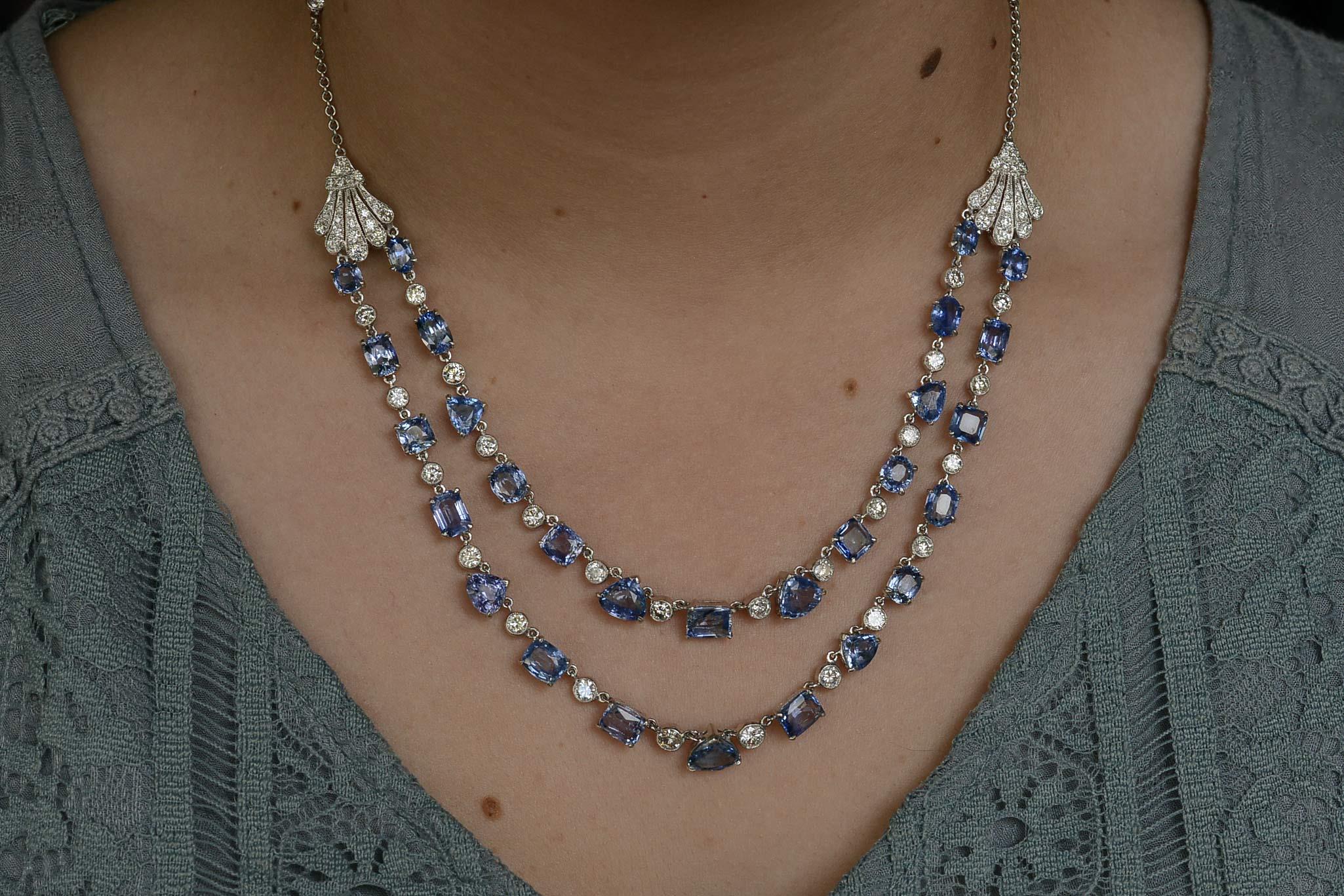 A most dramatic and elegant Art Deco style bib necklace. Fashioned of two tiers of velvety blue natural sapphires and fiery white diamonds that cascade like a waterfall. The 2 graduated strands set with 28 matching sapphires of 5 different cutting