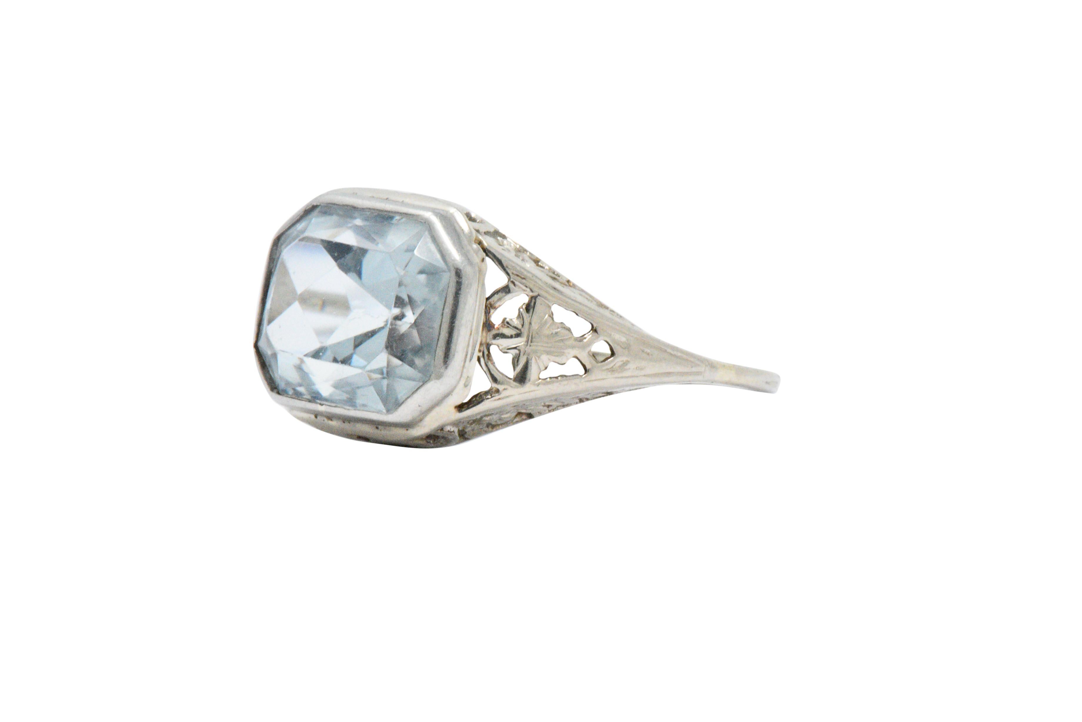 Centering a cut-corner, rectangular brilliant cut aquamarine, weighing approximately 4.00 carats, bright light blue

Bezel set with a pierced foliate and scrolling motif

Clean bright ring, yet so lovingly detailed

Ring Size: 6 1/4 & Sizable

The