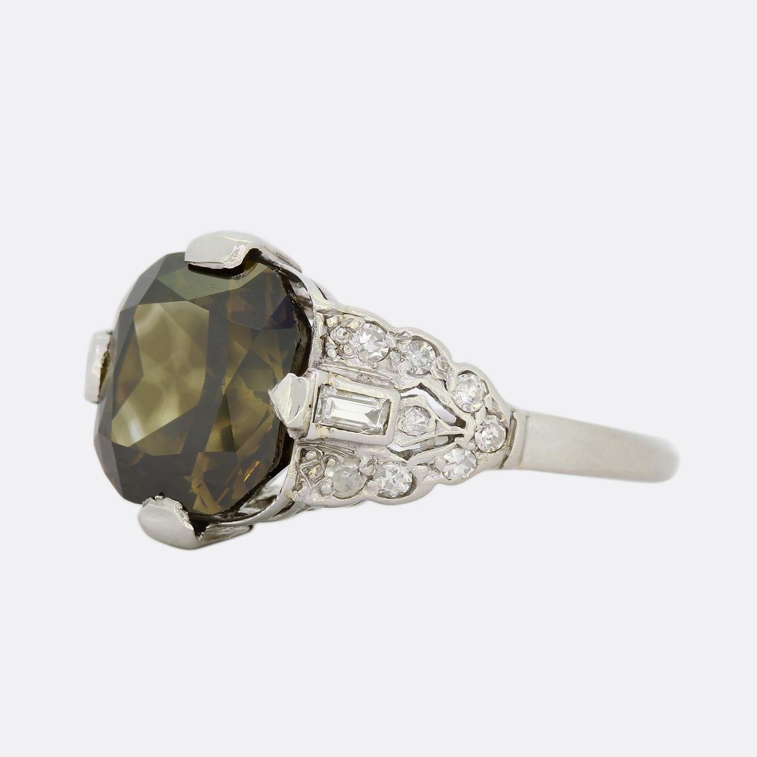 This is a wonderful diamond ring from the Art Deco period. The cushion cut diamond is a natural fancy dark yellow grey and sits in an Art Deco ring mount which has been set with baguette and single cut diamonds. If you want an engagement ring that's