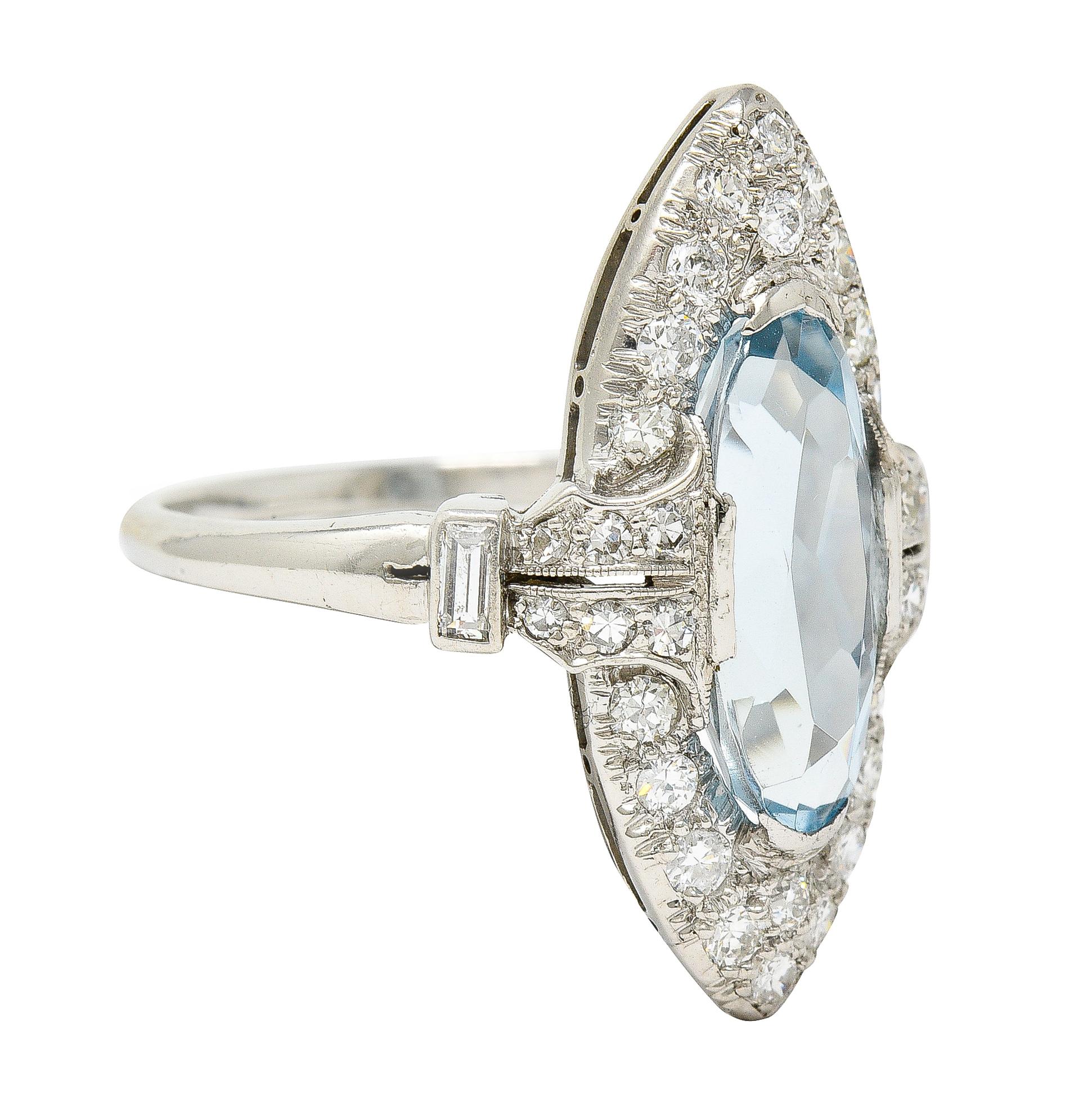 Centering a navette cut aquamarine weighing approximately 3.26 carats - transparent light blue in color 
Set with tab prongs with a surround of bead set clustered old European cut diamonds 
With additional old European and baguette-cut diamonds