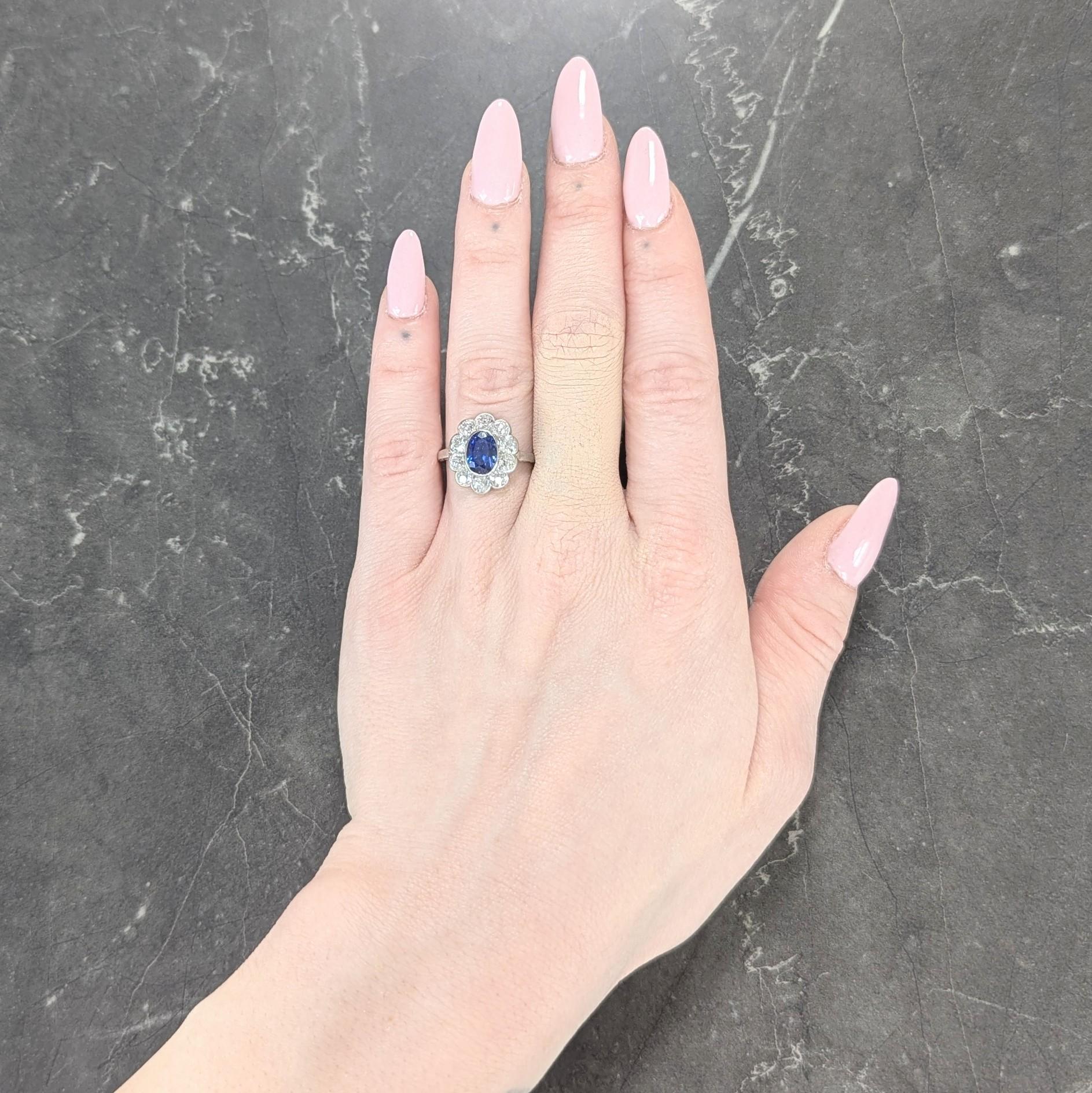 Centering an oval cut sapphire weighing 2.56 carats total - transparent vivid medium blue in color
Natural Ceylon (Sri Lankan) in origin and displaying no indications of heat treatment
Bezel set with a recessed halo surround of old mine cut