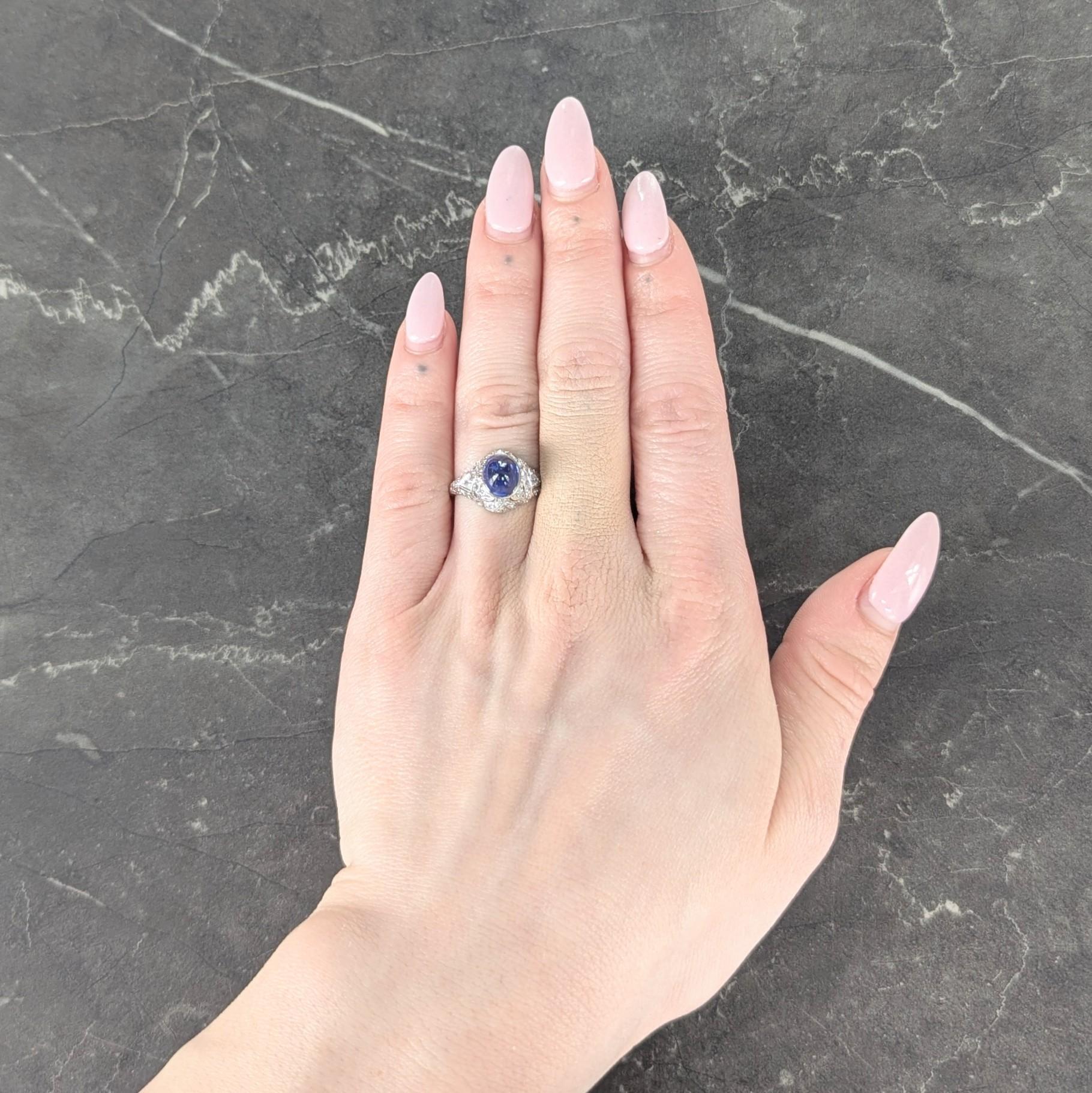 Centering a sapphire bullet cabochon weighing 3.30 carats total - transparent medium blue
Bezel set with a pierced bombé shaped surround with sweeping geometric pattern
Bead set with single cut diamonds weighing approximately 0.90 carat total - G