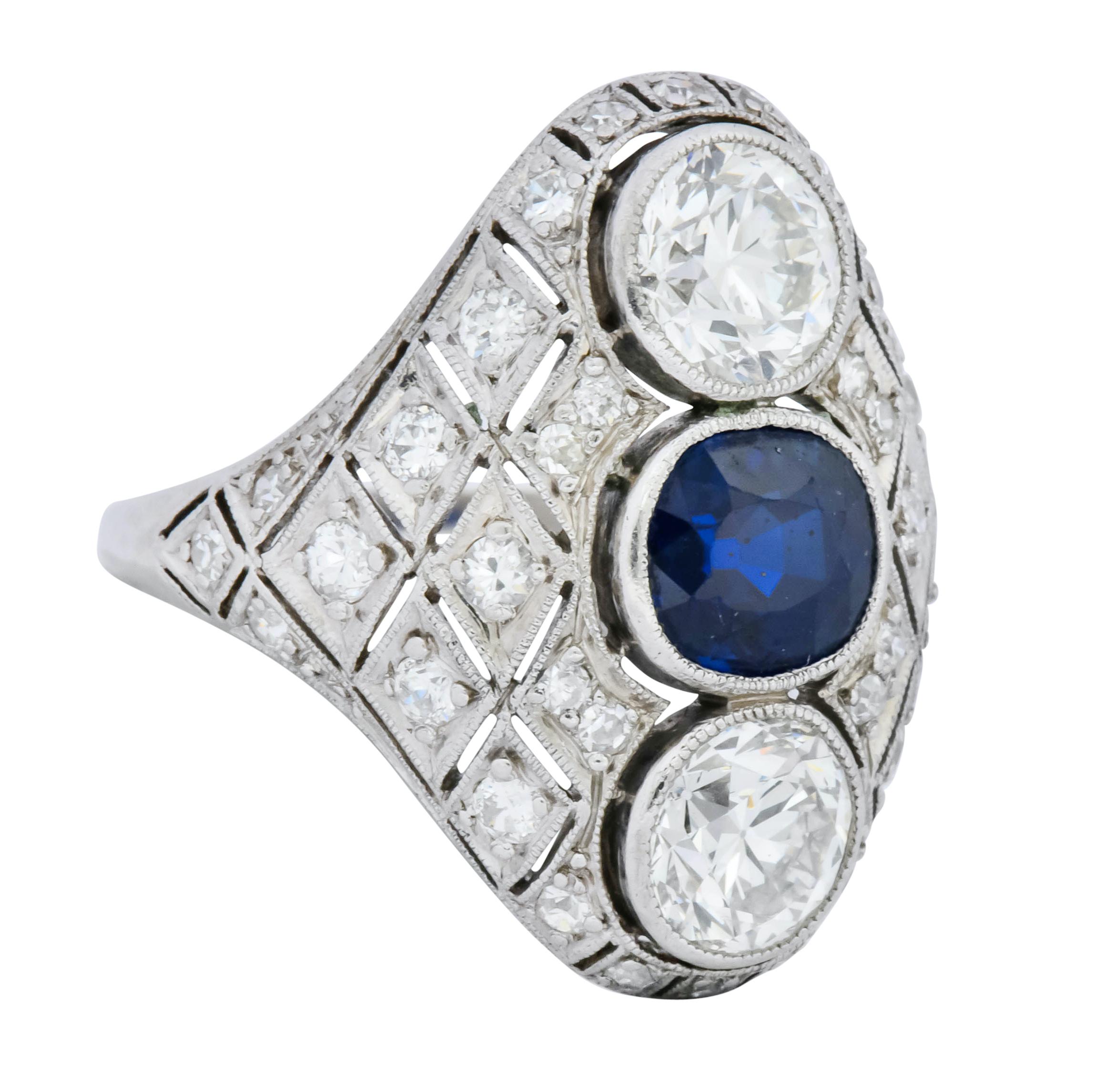 Centering a cushion cut sapphire weighing approximately 1.30 carats, transparent and a deep blue color

Flanked by two old European cut diamonds weighing approximately 1.80 carats, H-I color and VS clarity

All three bezel set North to South in a