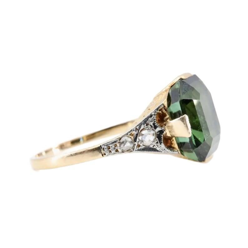 Aston Estate Jewelry Presents:

A beautiful handmade Art Deco period tourmaline, and diamond ring. Centering this ring is a 4.10 carat beautiful natural green tourmaline framed by four pave set rose cut diamonds. The diamonds weigh 0.14ctw and grade
