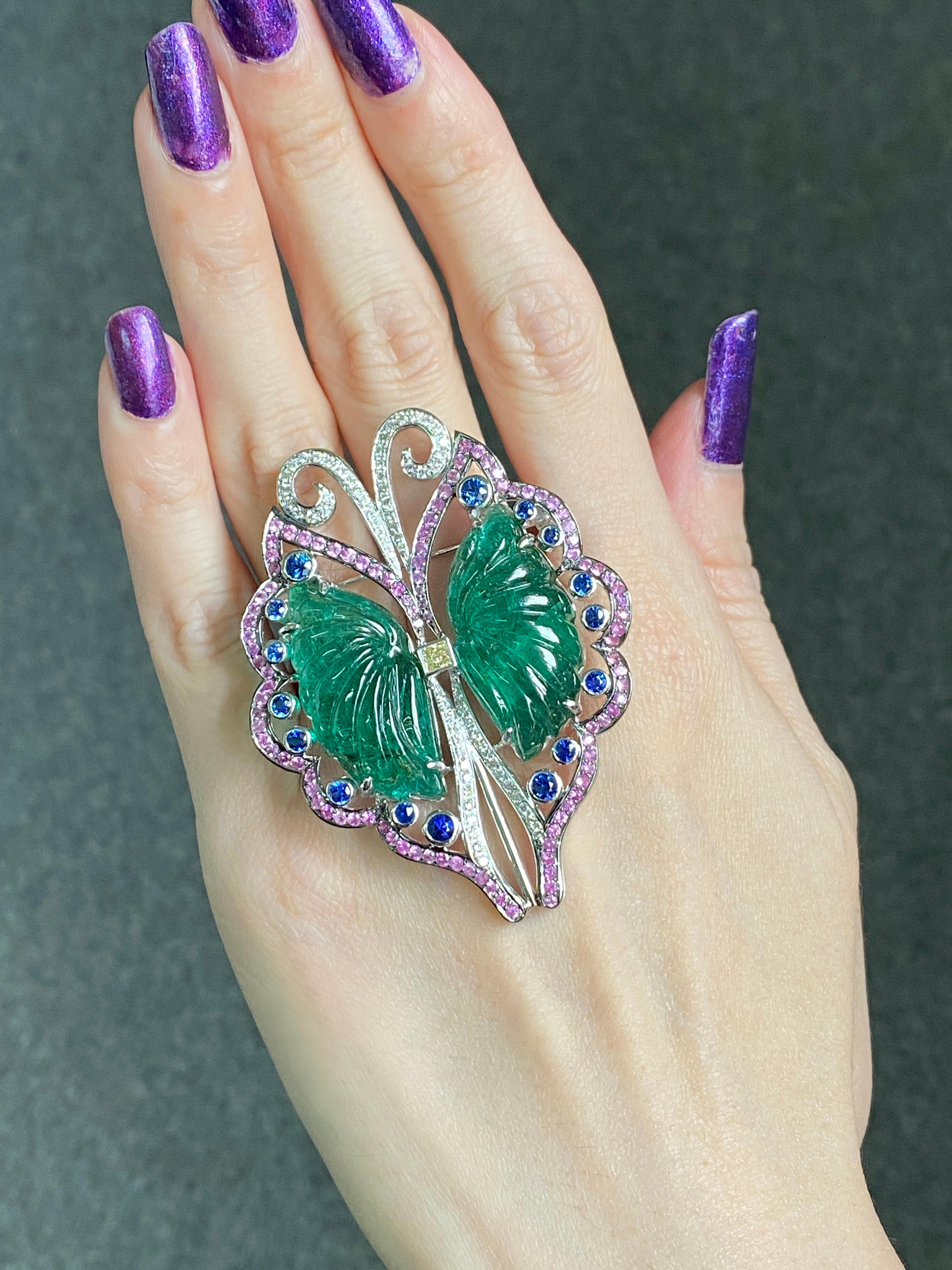 A beautiful, art-deco brooch with 42.77 carat carved, transparent, top quality Zambian Emeralds and pink and blue Sapphires, Diamonds set in solid 18K White Gold. The natural Emerald butterfly carved pieces are a work of art indeed , with only the