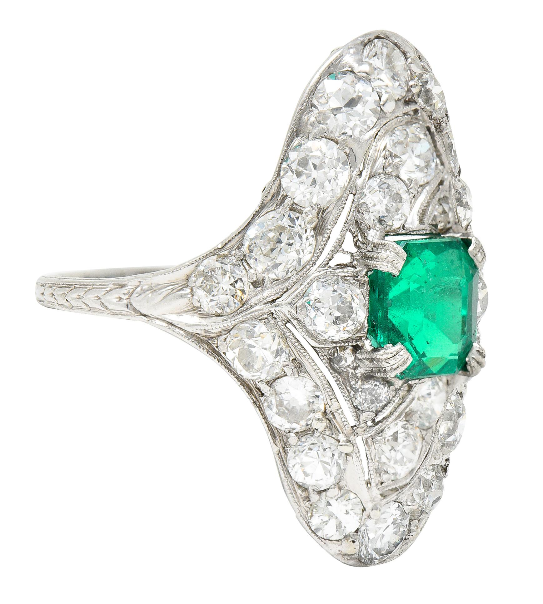 Centering an emerald cut emerald weighing approximately 1.53 carats total. Transparent well saturated bright green in color with natural inclusions - surface reaching. Set with milgrain detail prongs in a pierced wavy navette shaped surround. Bead