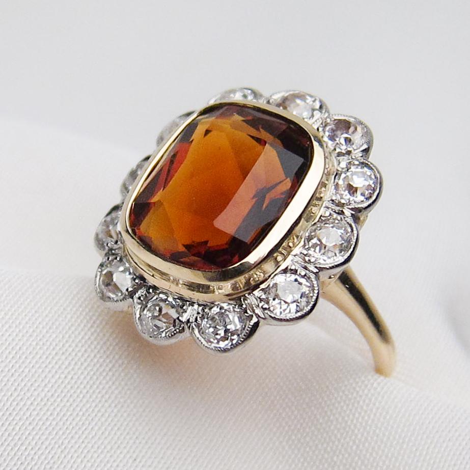 Circa 1920. This spectacular two-tone Art Deco Era halo ring features a 4.35 carat cushion mixed-cut natural orange citrine set in a gold bezel and surrounded with old European-cut diamonds weighing 1.5 carats. The accent diamonds are bezel and