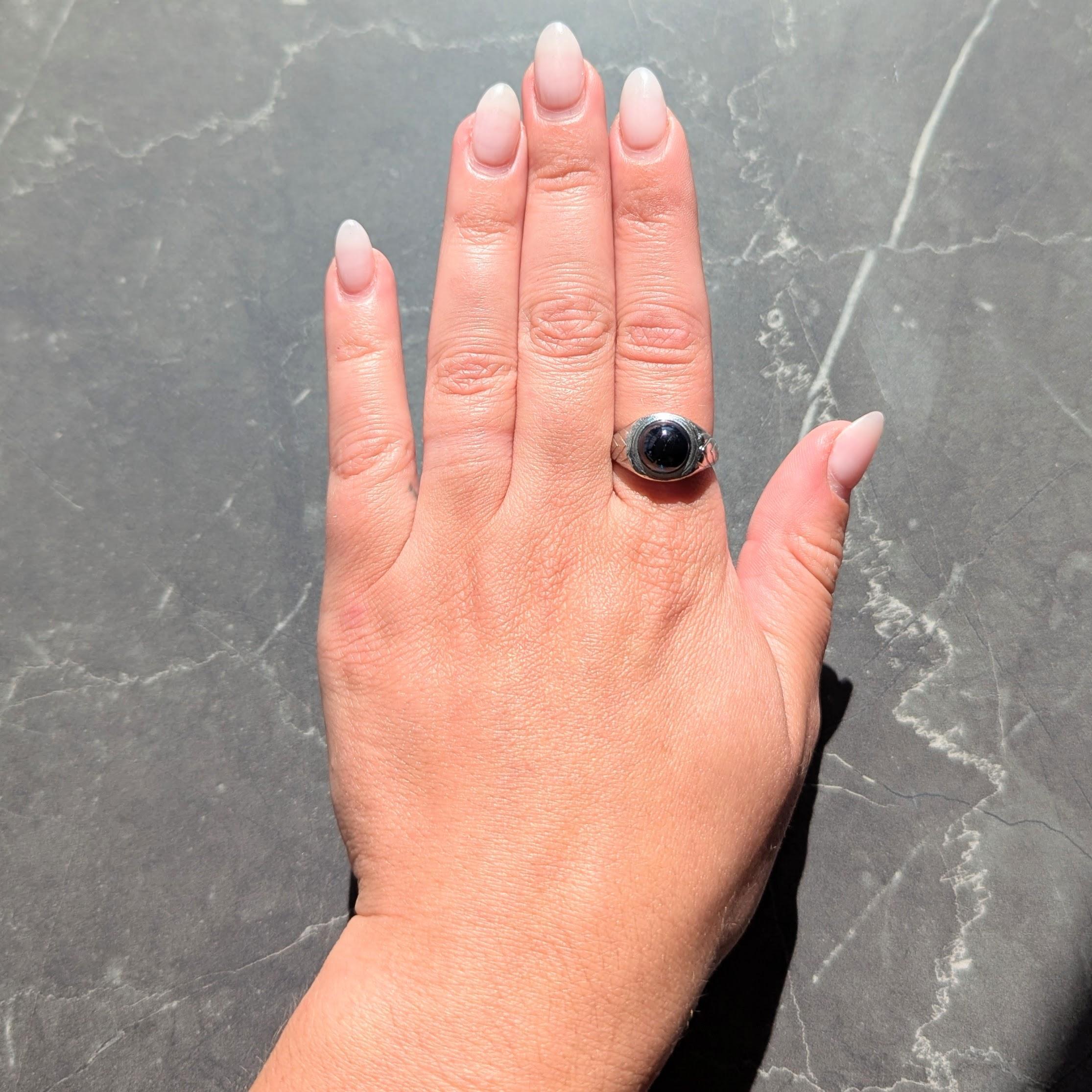 Au centre, un cabochon de saphir de forme ronde pesant environ 4,37 carats.
Semi-transparent de couleur bleu verdâtre foncé et serti à fleur avec un entourage gravé
Les épaules sont flanquées d'un motif à chevron gravé en gradins.
A.Profiles
Testé
