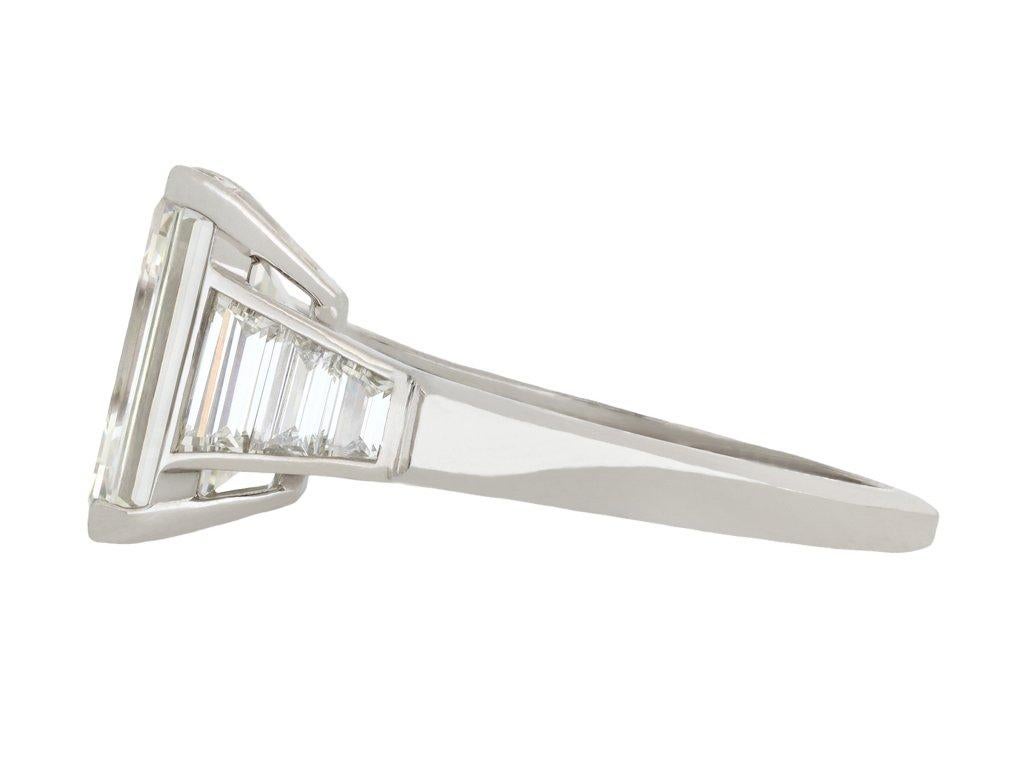 Solitärring mit Diamanten im Stufenschliff im Art Deco-Stil. In der Mitte befindet sich ein rechteckiger Diamant im Stufenschliff, Farbe G, Reinheit VS1, mit einem Gewicht von 4,38 Karat in einer offenen Klauenfassung, flankiert von sechs spitz