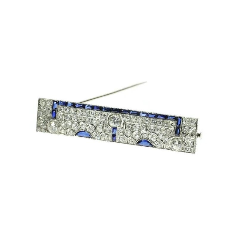 This Art Deco platinum brooch is gifted with a dispersive allure by the 72 old European and single brilliant cut diamonds pave set in a millegrain pierced geometrical design. A row of 19 rectangular cabochon sapphires connect three grand old