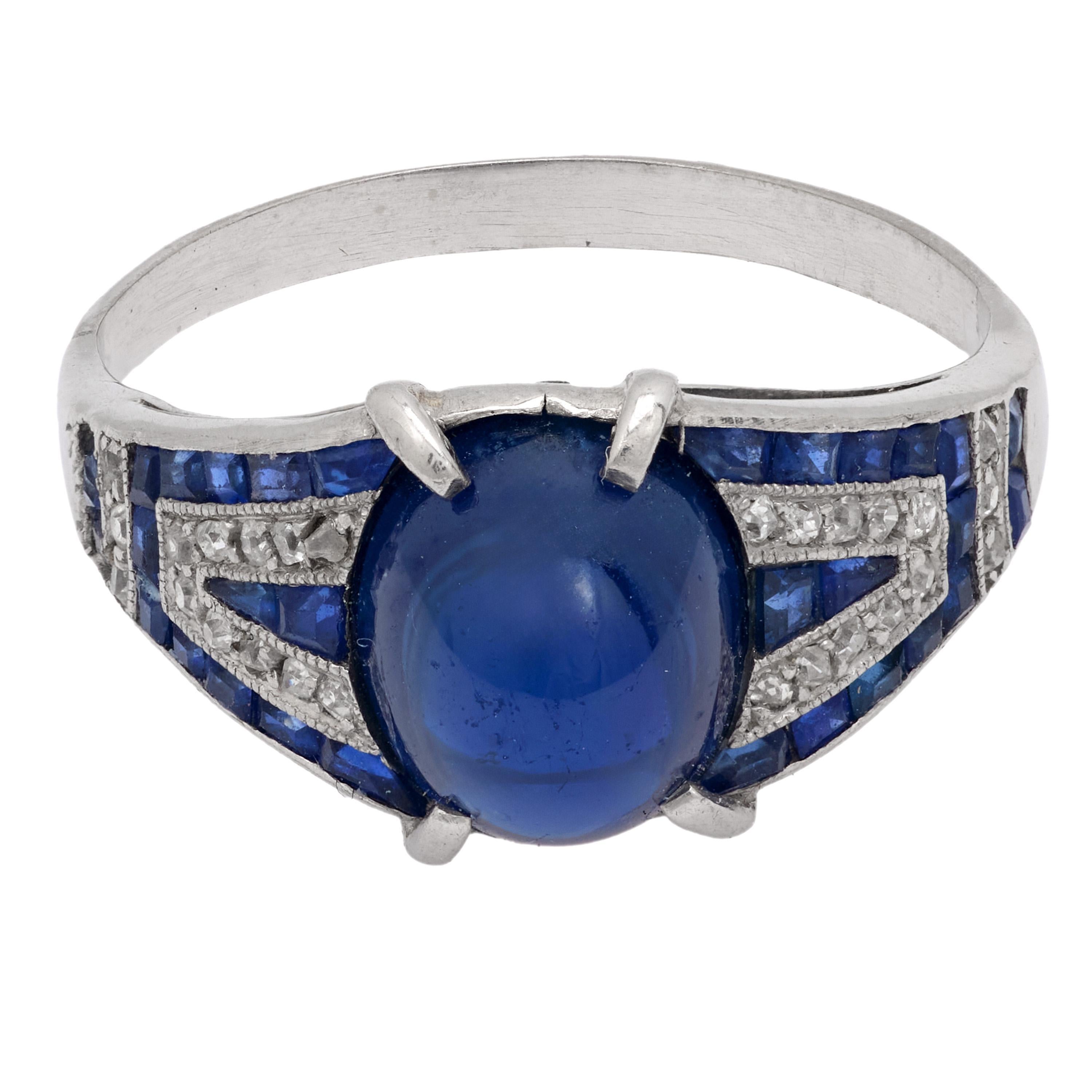 Superbe bague Art déco en platine avec un saphir cabochon de 4,50 carats, encadré par des saphirs de calibre et des diamants de mine ancienne étincelants dans une monture géométrique.