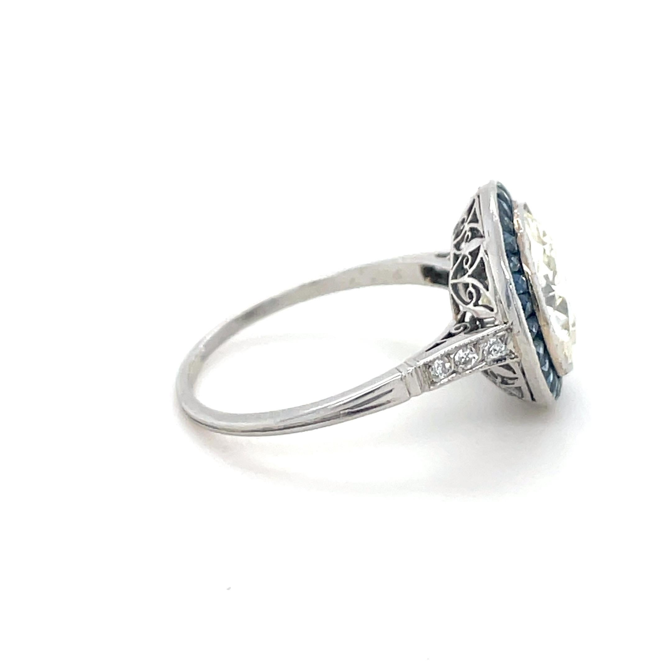 This beautiful and authentic Art Deco diamond engagement ring boasts an Old European cut diamond weighing 4.53 carats in a French cut sapphire surround and 6 old European cut diamonds on the shoulders. Mounted in platinum, with a swirling open
