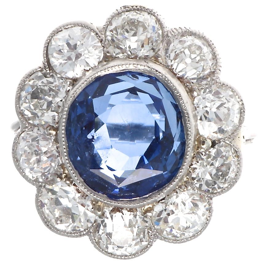 The iconic cluster design that is modeled after a blossoming daisy. Featuring a 4.82 carat GIA certified Burma sapphire that has no indications of heat treatment and displays a deep vivid blue color. Surrounded by pedals of old cut near colorless