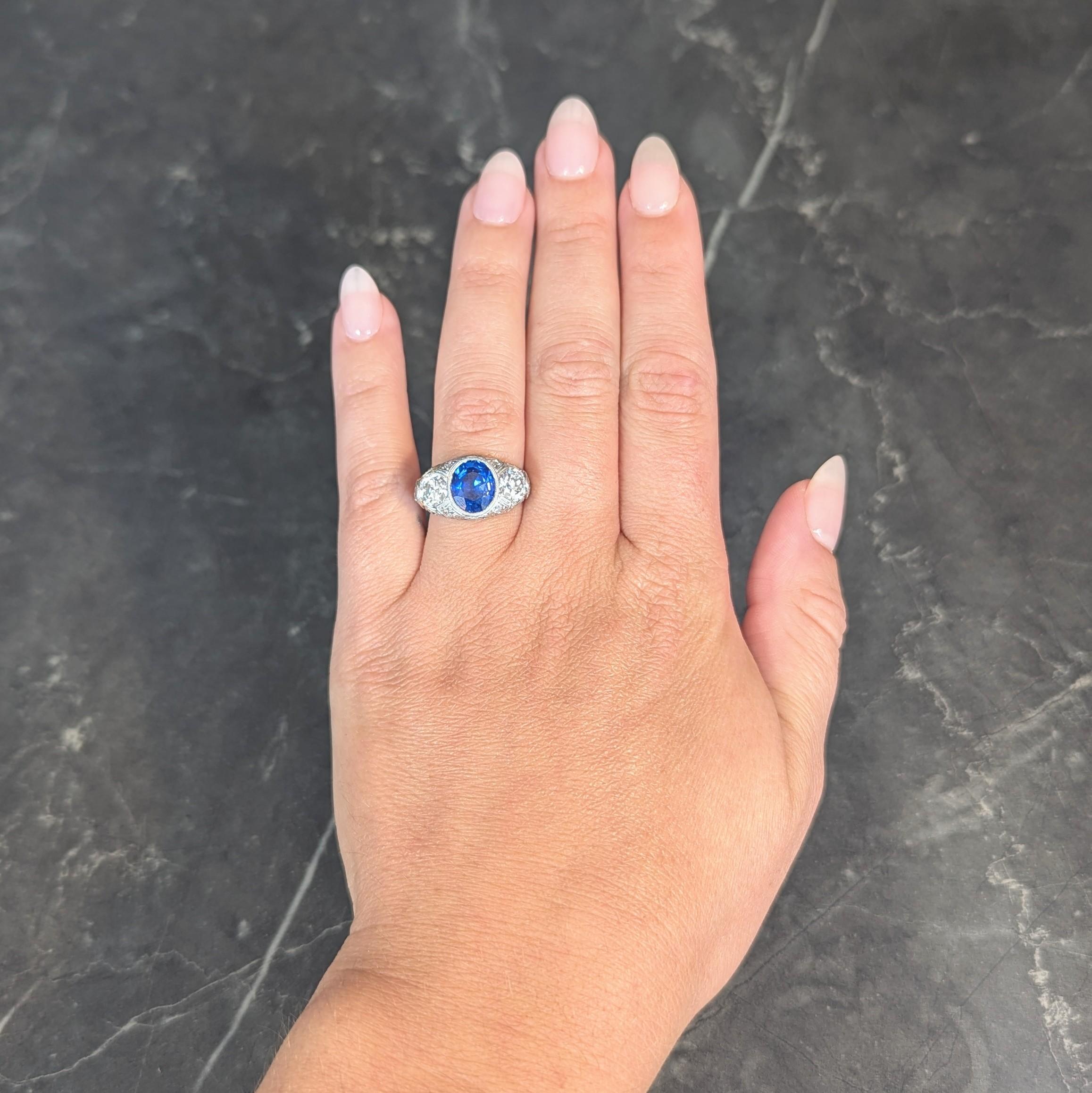 Centering an oval cut sapphire weighing 3.00 carats total - transparent vivid blue 
Natural Ceylon (Sri Lankan) in origin and displaying no indications of heat treatment
Set in a milgrain bezel and flanked east to west by old European cut diamonds