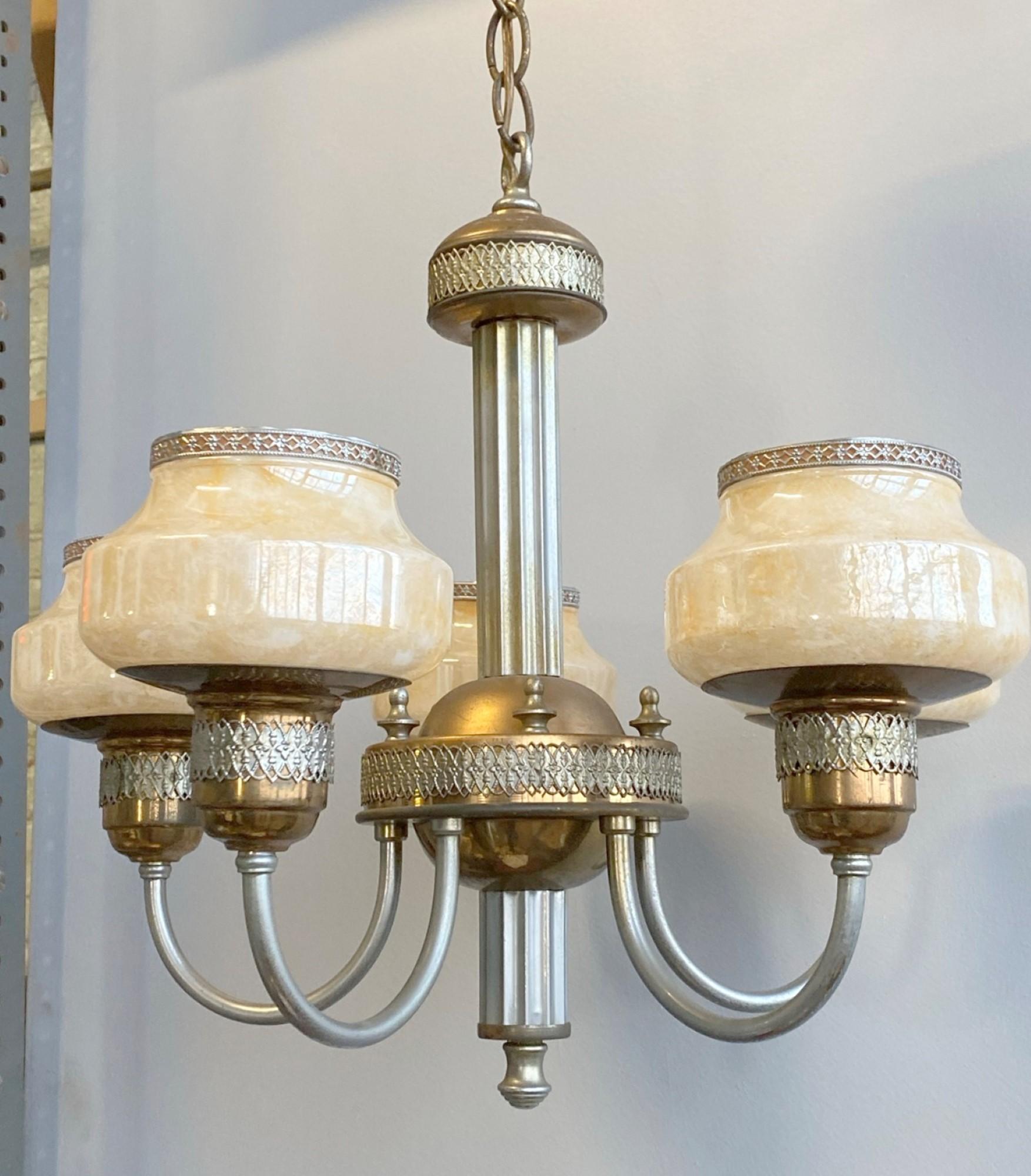 Early 20th century Art Deco five arm chandelier with a copper and nickel plated frame, iridescent honey colored custard glass shades and metal lace-like detail. This can be seen at our 400 Gilligan St location in Scranton, PA.