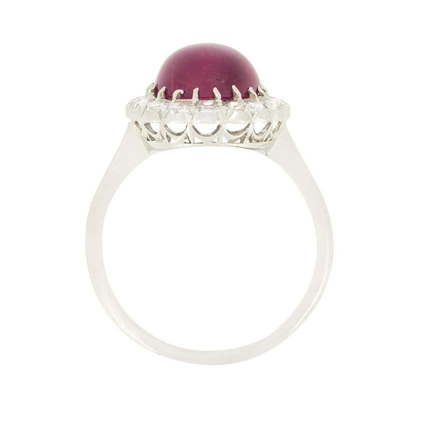 Dating back to the 1920s this wonderful cluster ring features an enchanting pink tourmaline at its centre. The cabochon cut gem weighs an impressive 5.00 carat and is claw set into platinum. Contrasting the tourmaline beautifully, a halo of eight