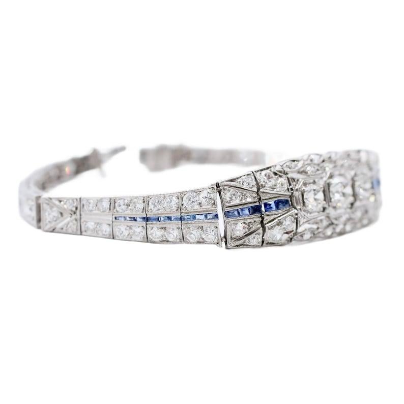 Aston Estate Jewelry Presents:

A glamorous art deco period diamond bracelet in platinum. Centered by a trio of old European cut diamonds of 1.00ctw with G color and VS2 clarity. Accented by a row of tapered French cut sapphires, and pave set