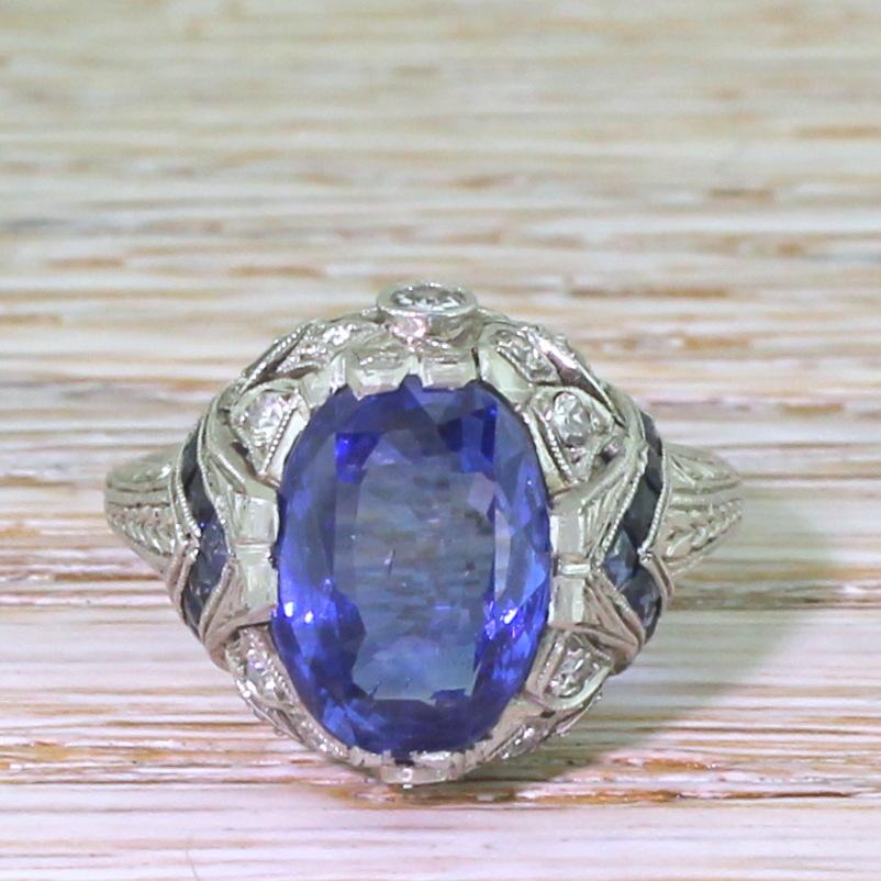 A top grade sapphire in an equally impressive mounting. The natural, no heat Ceylon sapphire in the centre displays the perfect cornflower blue; rich, bright, with clear flashes of violet and indigo. The stone in showcased in an exceptional highly