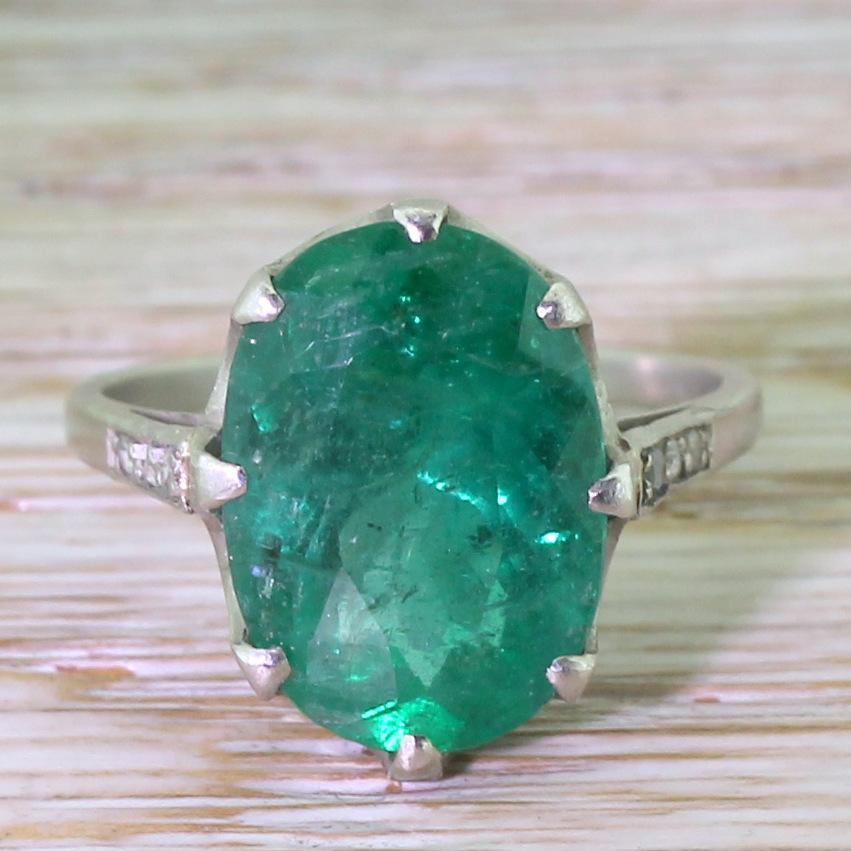 This gorgeous verdant and vibrant emerald is in an eight claw collet with a elegant crown gallery, leading to a slim band set with six (three either side) rose cut diamonds. A delight of a ring that can be worn as an alternative style solitaire, or