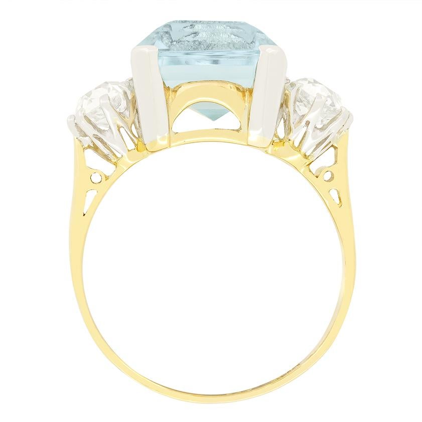 Dieser atemberaubende Trilogie-Ring aus den 1920er Jahren zeigt in seiner Mitte einen bezaubernden Aquamarin im Smaragdschliff. Der fachmännisch gefasste Aquamarin wiegt 5,50 Karat und wird von zwei Diamanten im Altschliff von je 0,50 Karat
