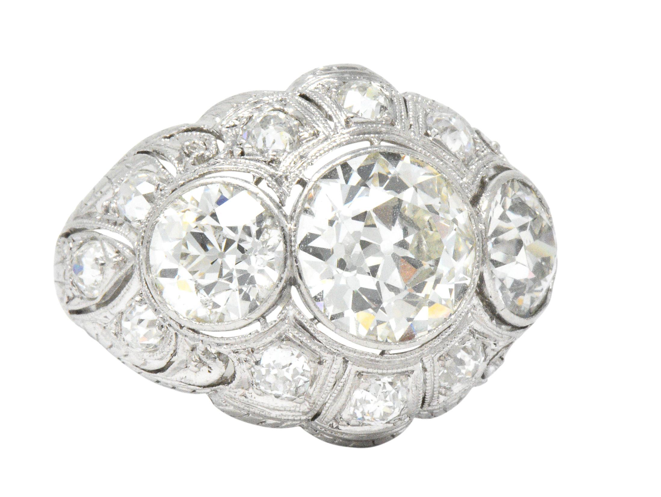 Pierced bombay style mounting with milgrain edges centers an old European cut diamond weighing approximately 2.50 carats, J color with VS clarity

Flanked by two additional old European cut diamonds weighing approximately 1.10 and 1.00 carats; both