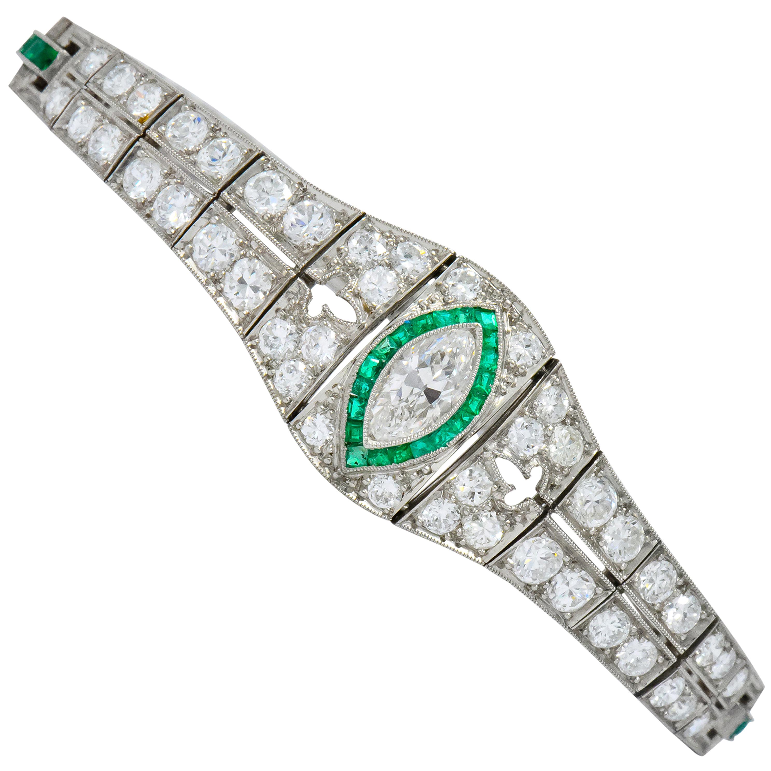 Centering a bezel set marquise cut diamond weighing approximately 0.62 carat, H/I color and VVS clarity

With calibré cut emerald surround, transparent with lush green color

Bead set throughout by round brilliant cut diamonds weighing approximately