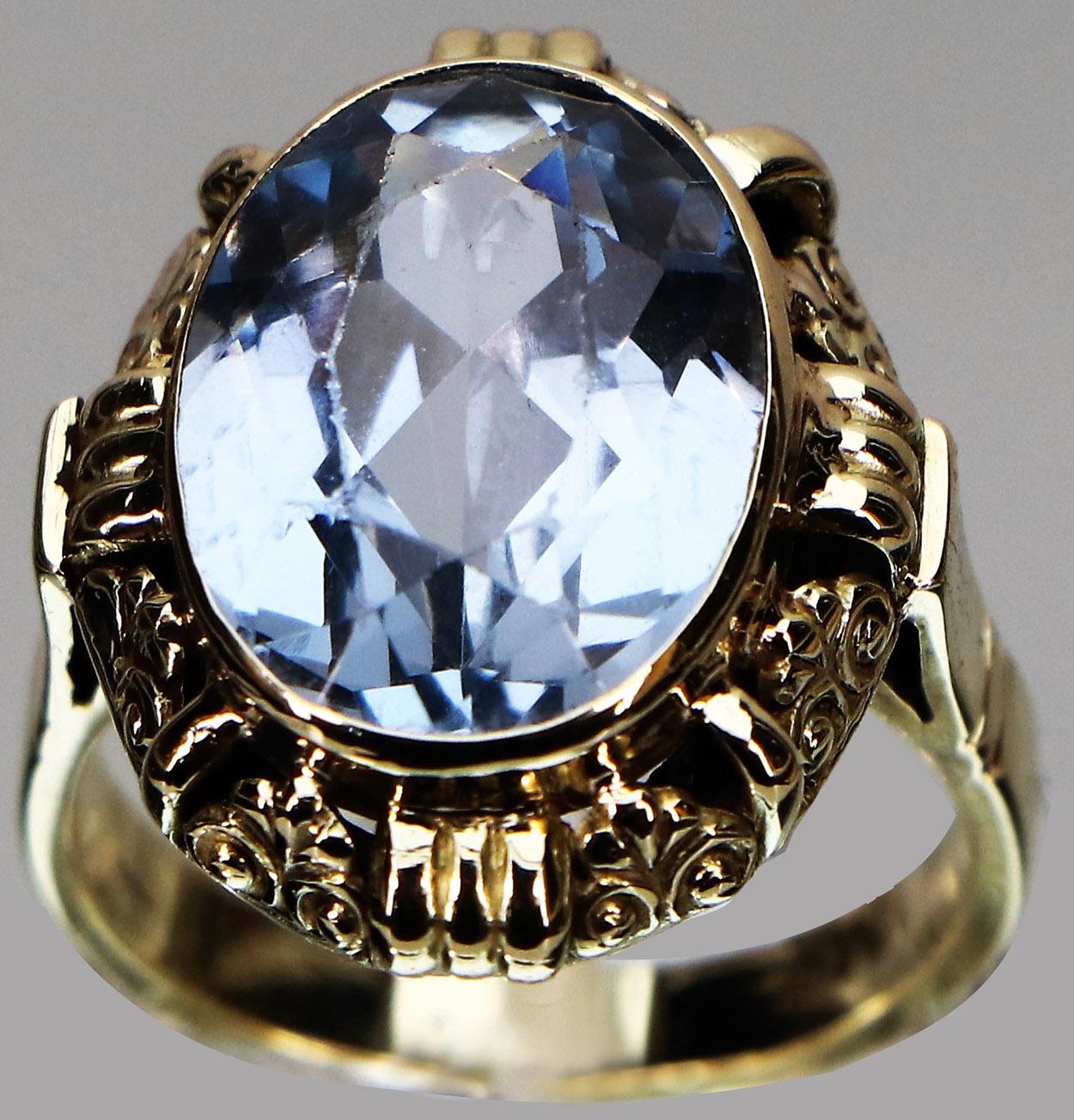 Statement ring with faceted blue topaz, set in a richly decorated frame and smooth ring band from the late Art Deco.
Very nice sculptural frame around the blue topaz.

Ring size: 53/17 mm
Ring Head Diameter: 20.2mm x 16.2mm
Wide ring binder on the