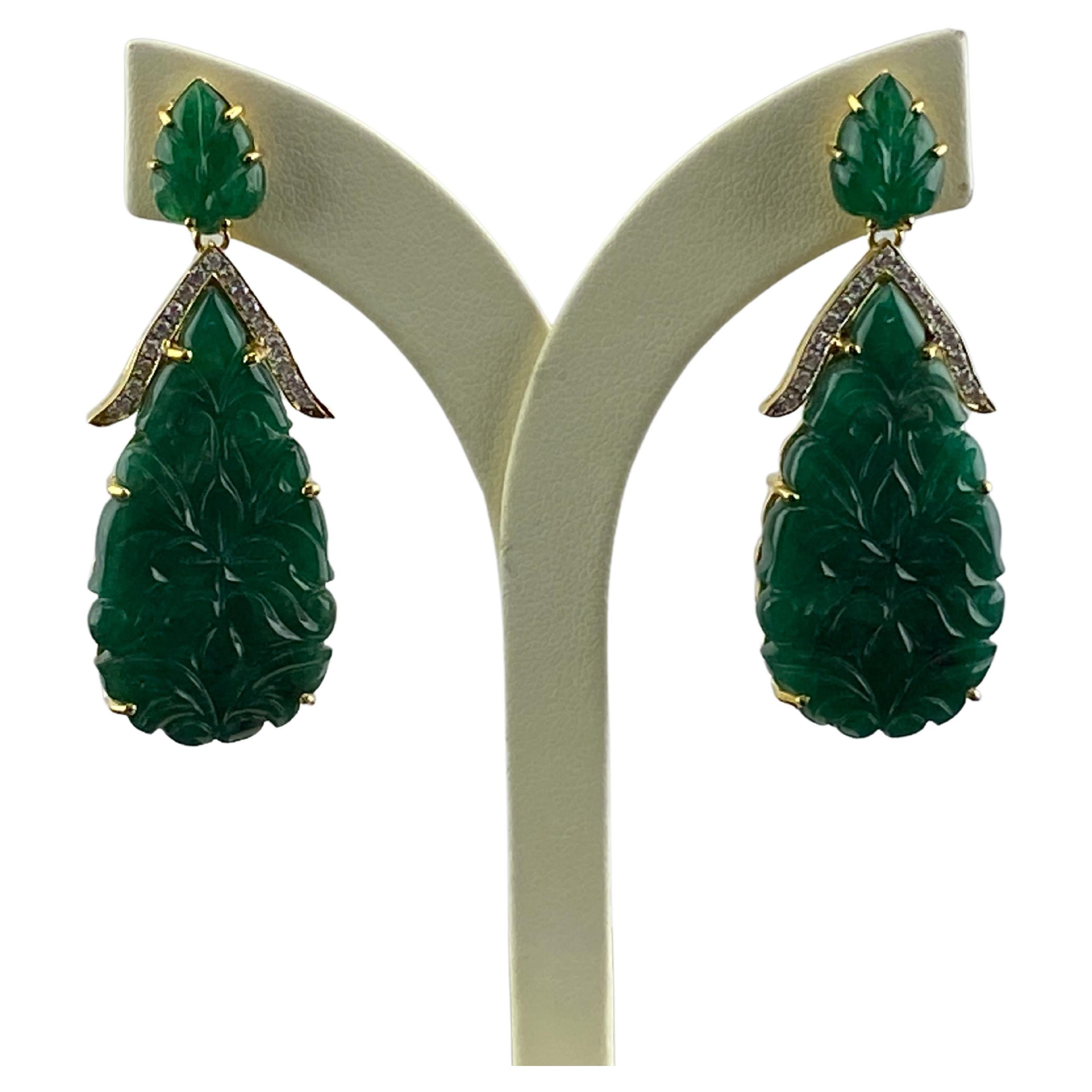 An art-deco style 59.83 carat carved Zambian Emerald dangle earrings, with 0.51 carat White Diamonds all set in 18K Yellow Gold. The earrings come with a push-pull backings, and this pair of earrings can be customized according to your
