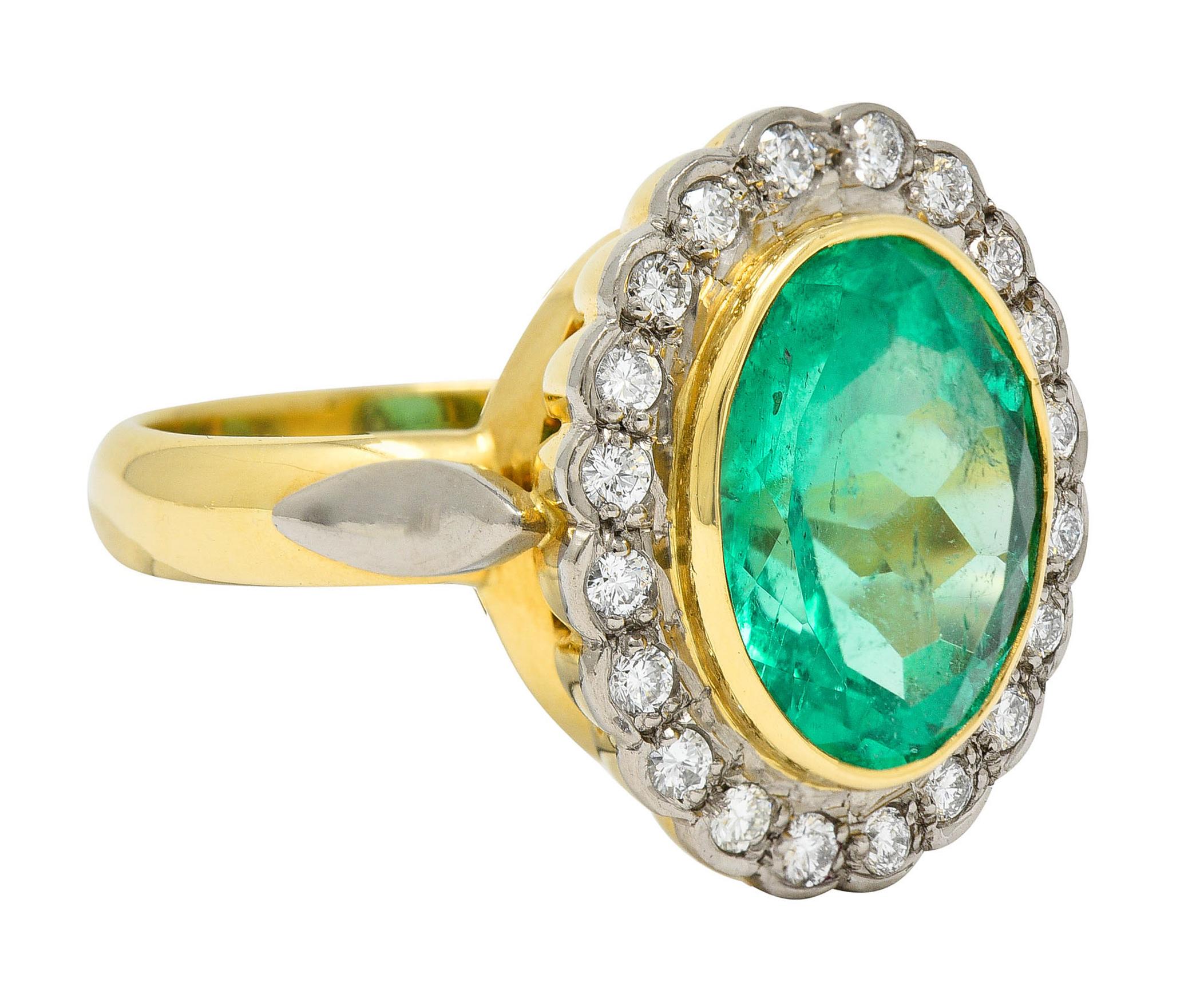 Centering a mixed oval cut Colombian emerald weighing approximately 5.55 carats

Semi-transparent and vibrantly green in color with minor enhancement

Bezel set in a polished gold surround with a round brilliant cut diamonds halo - set in scalloped