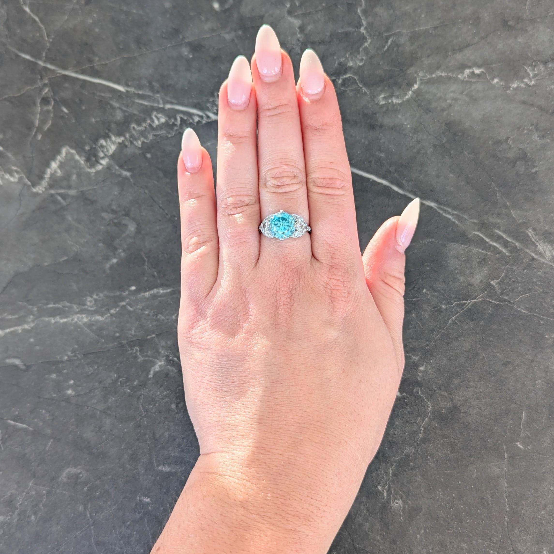 Centering a round cut zircon weighing approximately 5.79 carats
Transparent vibrant medium greenish blue in color
Prong set in basket and flanked by pierced shoulders
Flanked by bezel set old European cut diamonds
Weighing approximately 0.24 carat