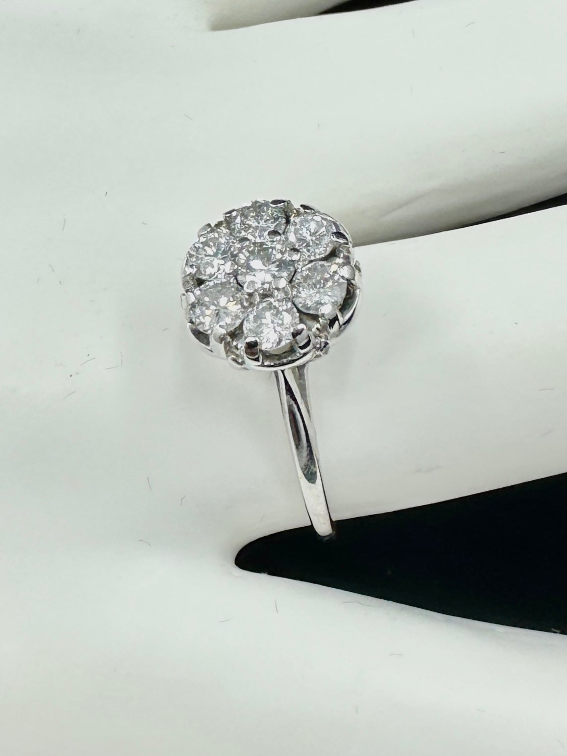 Dies ist ein atemberaubender und dramatischer antiker Art-Deco-Diamant-Verlobungsring in 14 Karat Weißgold mit sieben wunderschönen runden Diamanten von hervorragender Brillanz.  Die Diamanten sind in einem Blumencluster-Motiv mit einem