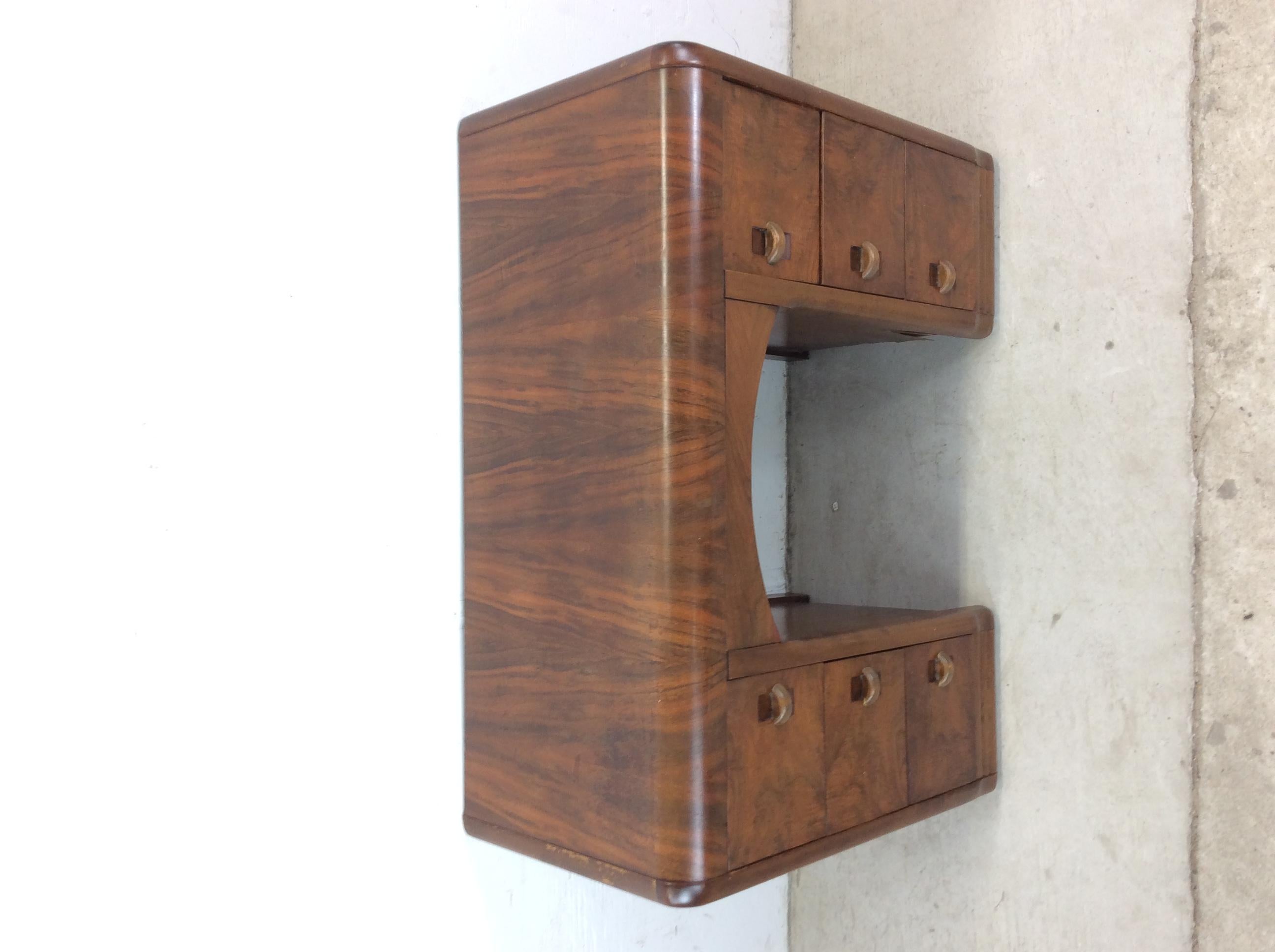 This antique art deco vanity features hardwood construction, walnut veneer with original finish, seven dovetailed drawers with unique bentwood pulls, and a waterfall top.

Dimensions: 38.5w 16.5d 28h 23.5kh

Condition notes: Original finish has some