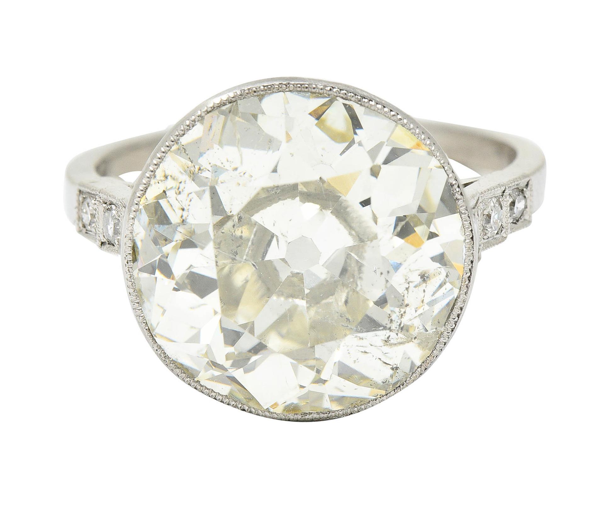 Centering an old European cut diamond weighing 7.06 carats - M color with SI2 clarity

Bezel set in a milgrain surround and flanked by stepped cathedral shoulders

Accented by single cut diamonds weighing in total approximately 0.15 carat - H/I