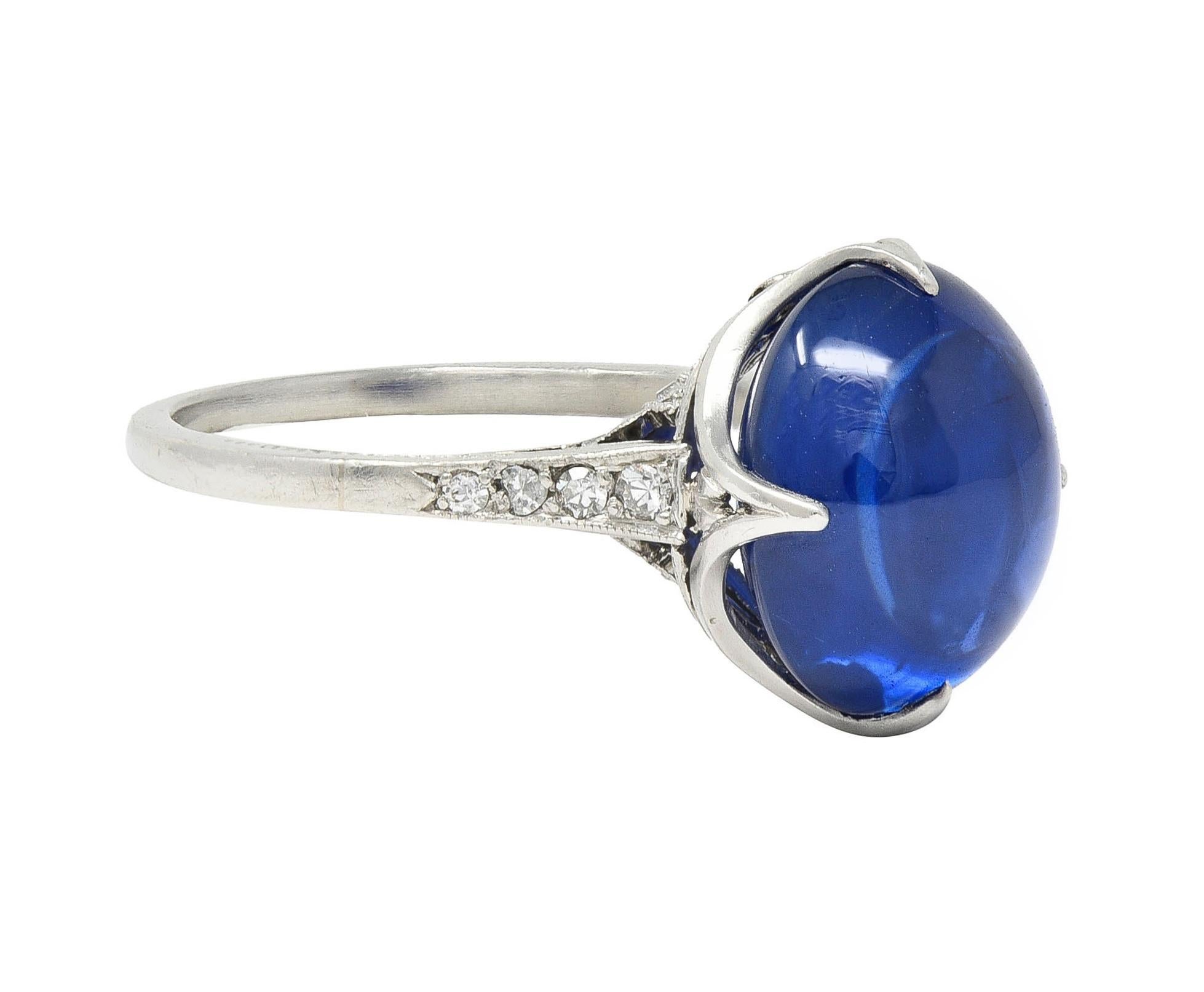 Centering an oval-shaped sapphire double cabochon weighing approximately 7.19 carats
Transparent vibrant medium blue in color - set with talon prongs in pierced gallery
Depicting tied ribbon with flaring tails in profile - flanked by cathedral