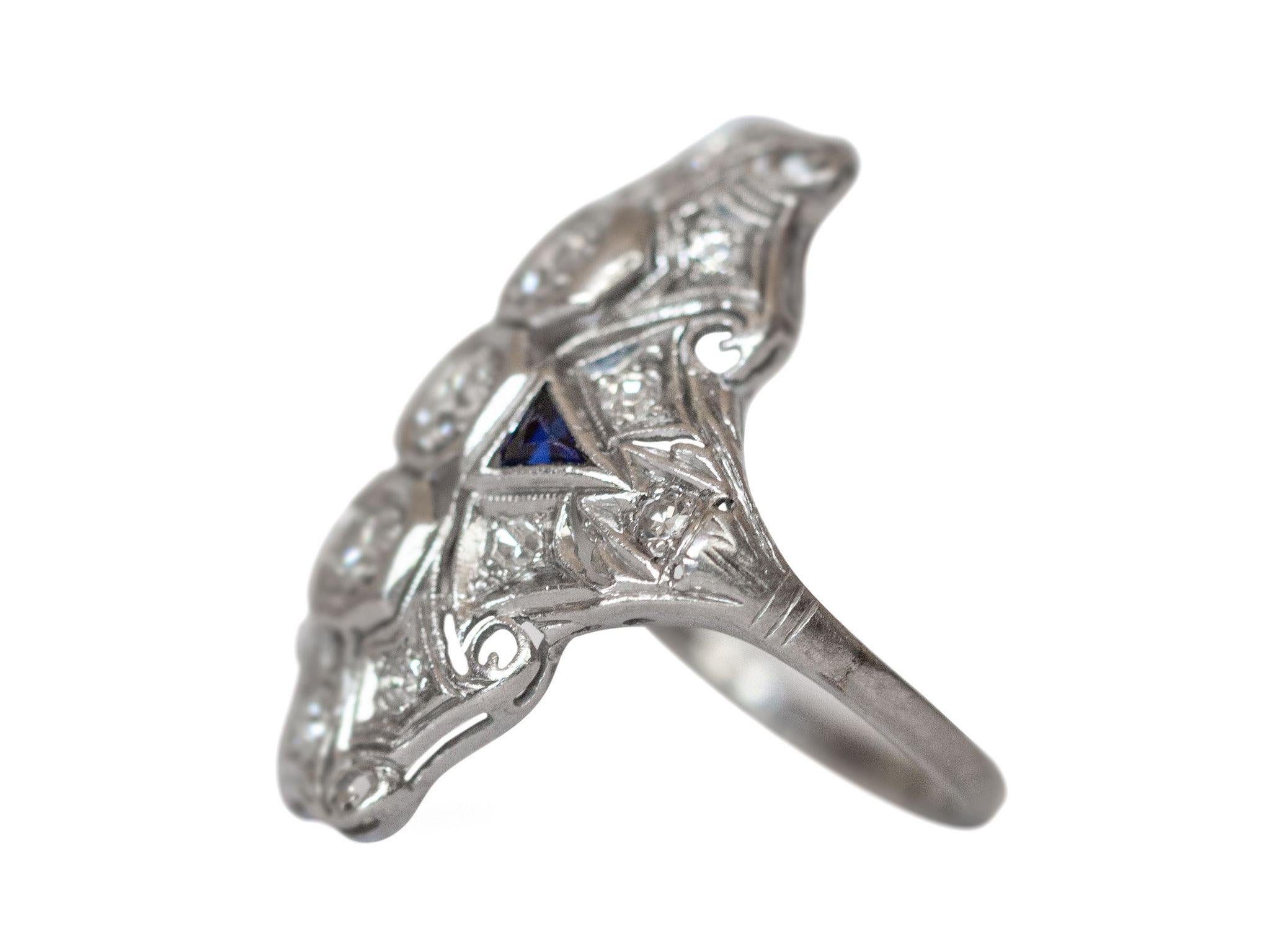 This lovely example of an Art Deco shield ring is crafted of stunning platinum. Intricate filigree designs surround 3 sparkling diamonds on this vintage beauty. Two sapphire pyramids add a pop of color that adds to this already beautiful piece. This