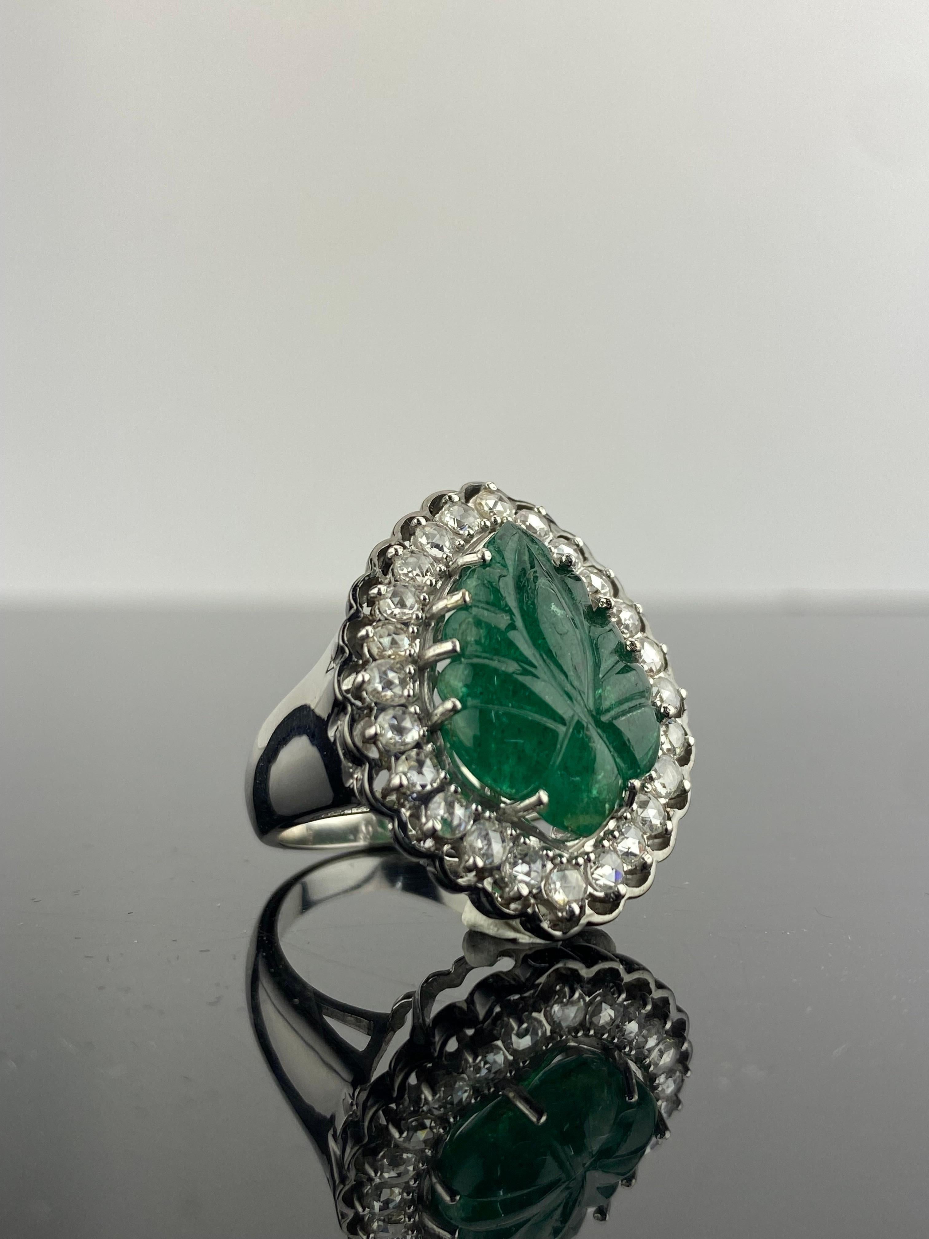 
An art-deco inspired statement cocktail ring, with a 8 carat carved Zambian Emerald center stone, and 1.03 carat White Diamond all set in solid 18K White Gold, with Black Rhodium polished rim. The center stone is a beautifully hand-carved natural