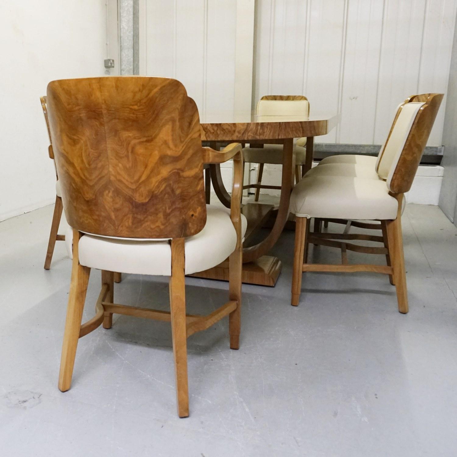 An Art Deco 8-seat dining suite attributed to Heal's of London. Dining table consists of two drop in leaf's in the centre. Six burr walnut backed dining chairs and two burr walnut and solid walnut framed armchairs. Burr walnut and figured walnut