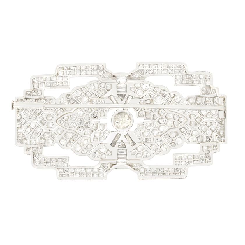 Questa squisita spilla è un capolavoro di precisione geometrica, icona dell'epoca Art Déco. Il cuore è costituito da un diamante taglio vecchio da 0,70 carati incastonato, incorniciato da eleganti linee di diamanti taglio baguette per un totale di