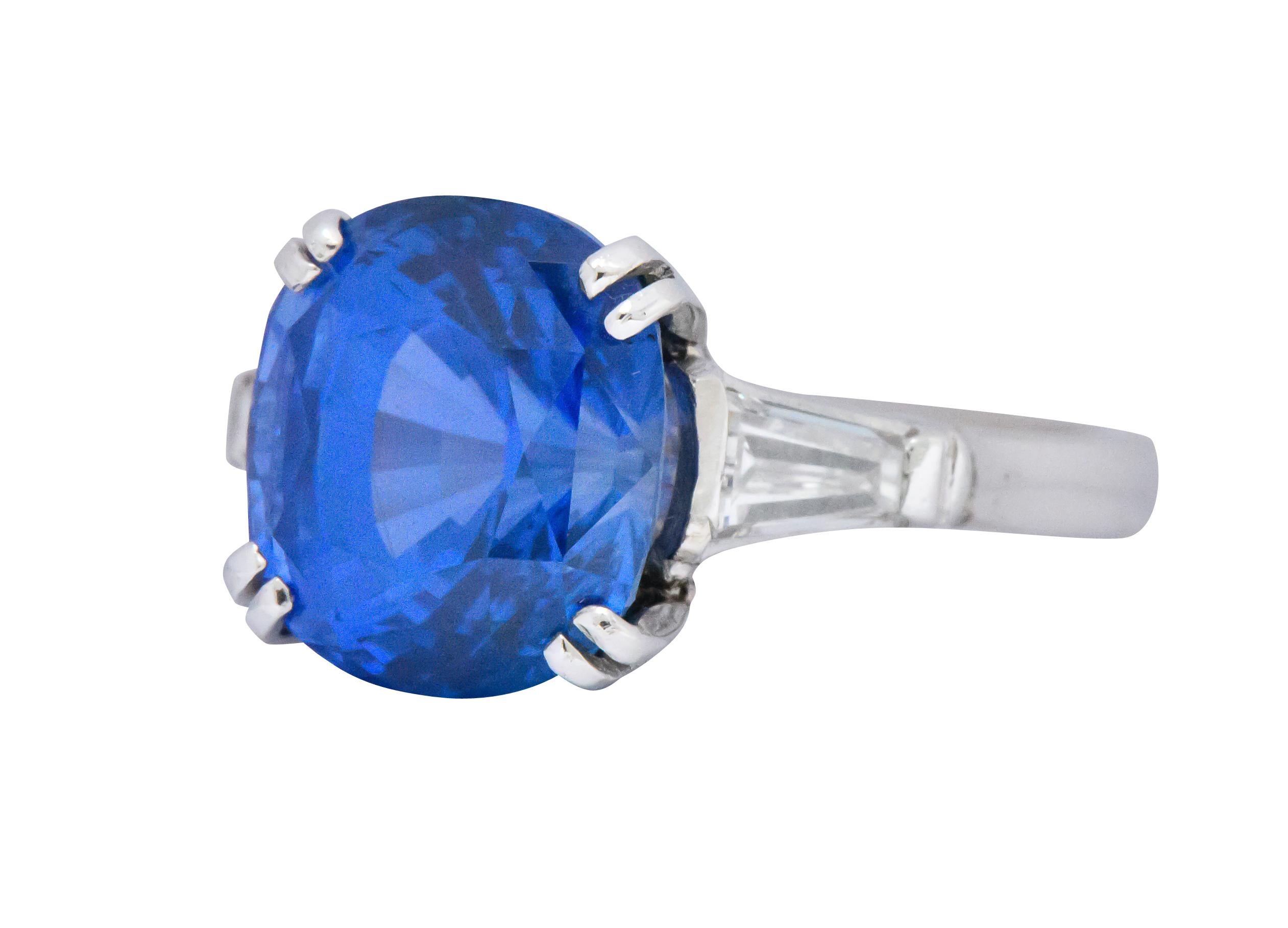 Centering a basket set cushion cut Ceylon sapphire weighing 8.12 carats, bright blue in color with no evidence of heat

Flanked by two tapered baguette cut diamonds weighing approximately 0.50 carat total, G/H color with VS clarity

Cathedral style