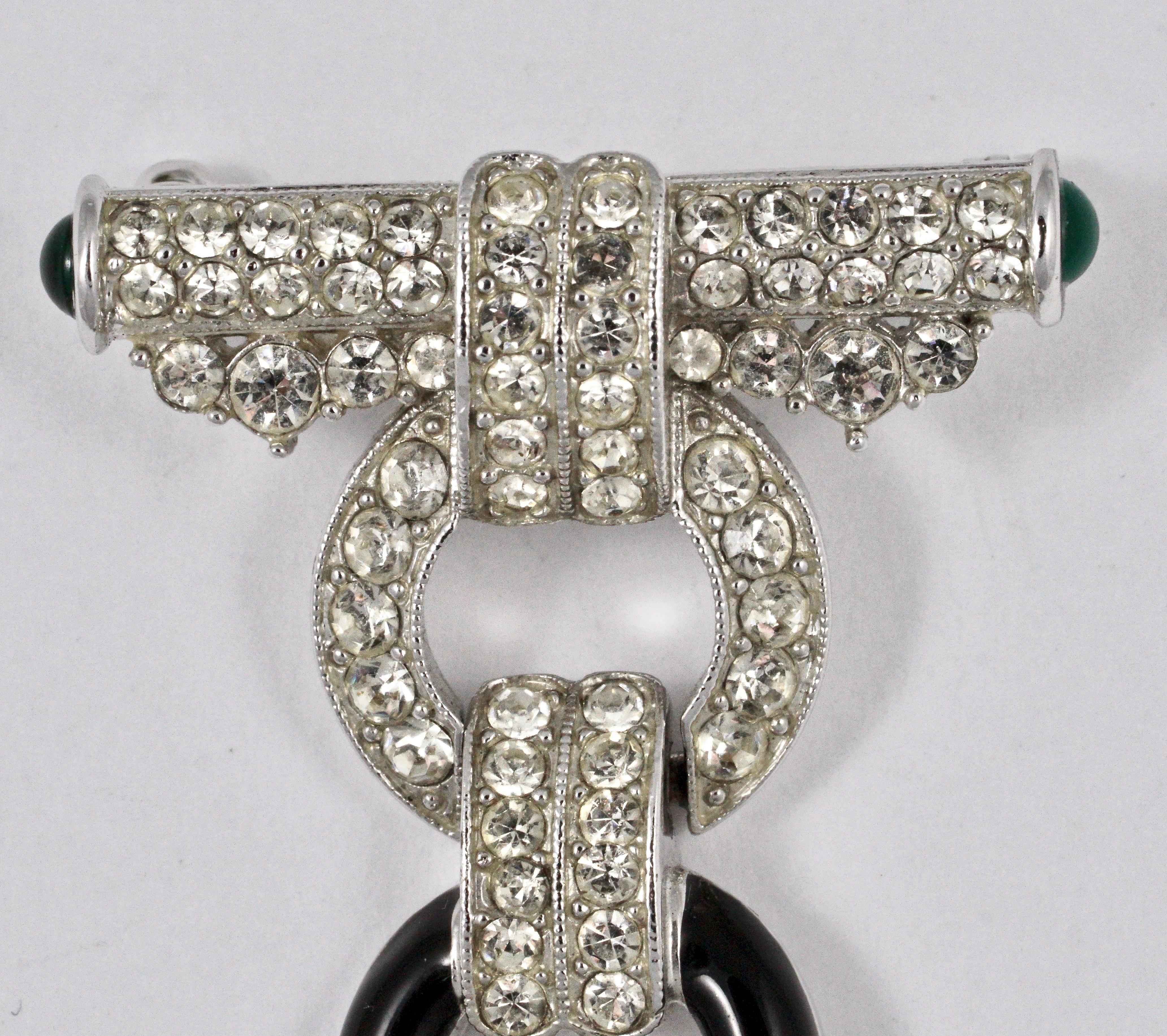 
Art Deco 89 fabulous silver tone brooch, featuring a drop with three circles and a rectangular pendant with the letters A D C, serial number B454. The brooch is embellished with clear rhinestones, and has black enamel highlights. The top of the
