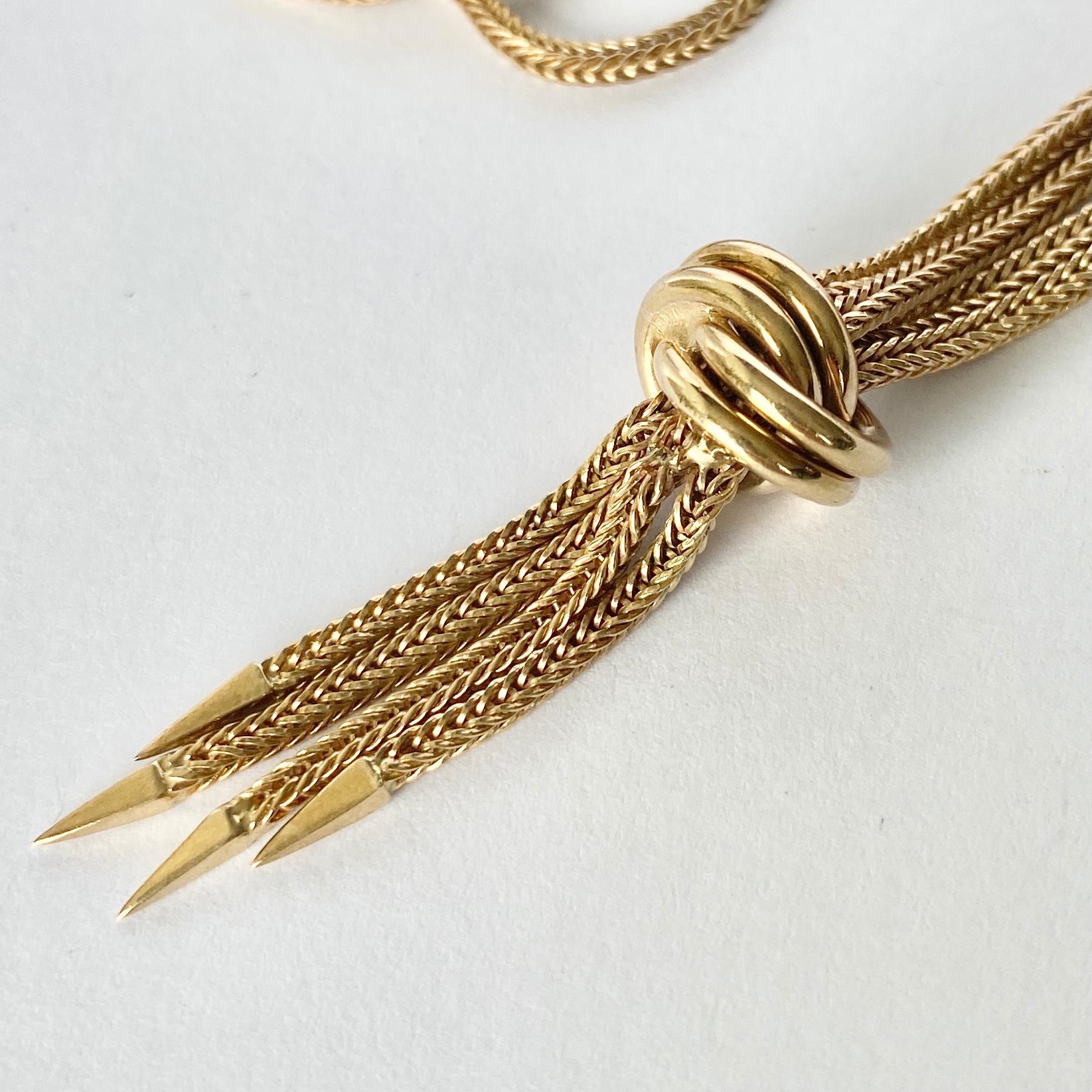 This 9ct yellow gold necklace is made up of snake like link chain and fastens using a bolt clip. At the centre of the chain is a gold knot and then a tassel which falls beautifully from it. 

Length: 41cm 
Chain Width: 2mm 

Weight: 15g
