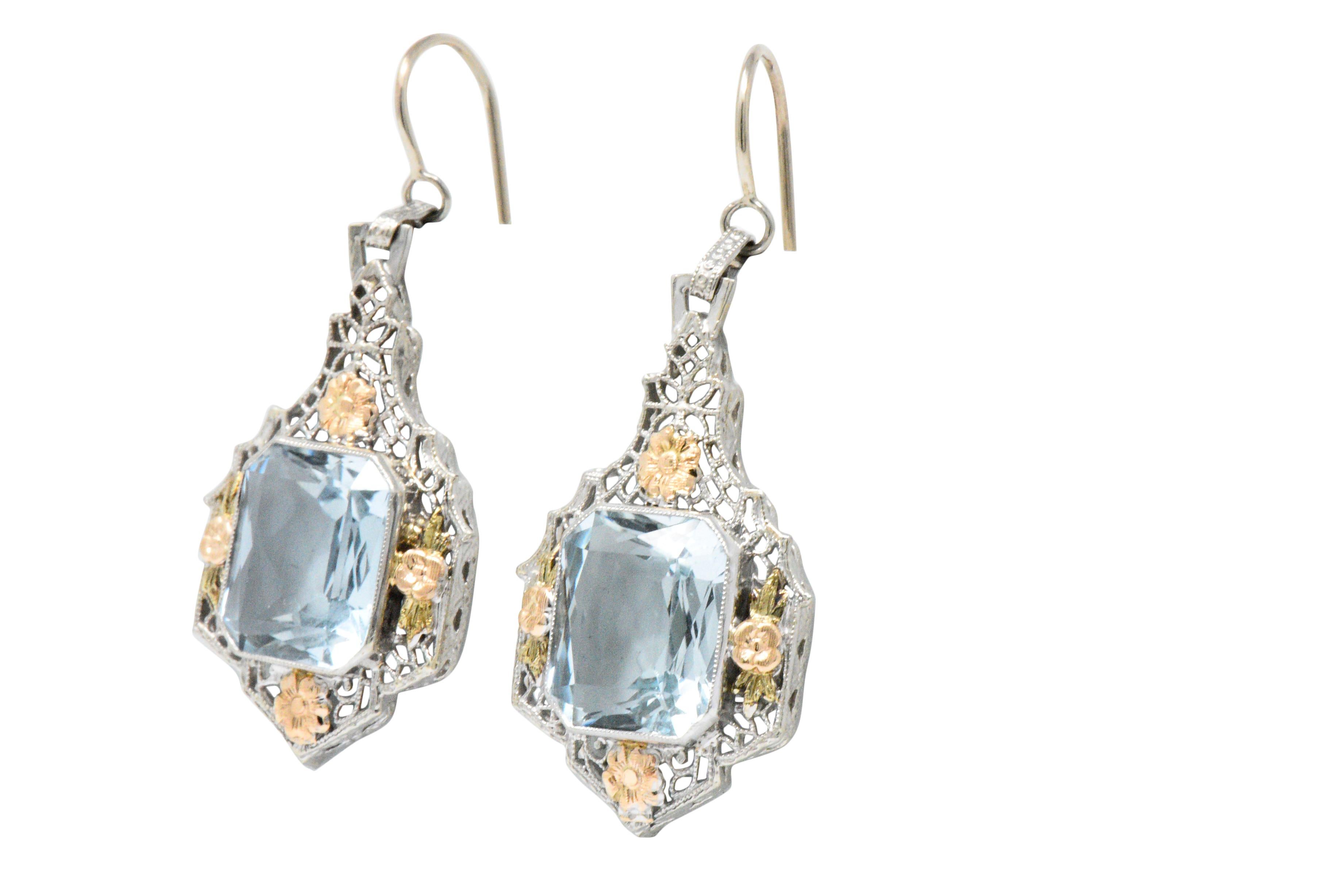 Each centering a cut-corner rectangular brilliant cut aquamarine, approximately 9.00 carats total, bright light blue, very well matches

The aquas are bezel set and accented by rose gold flowers with green gold leaves in a pierced millegrain white